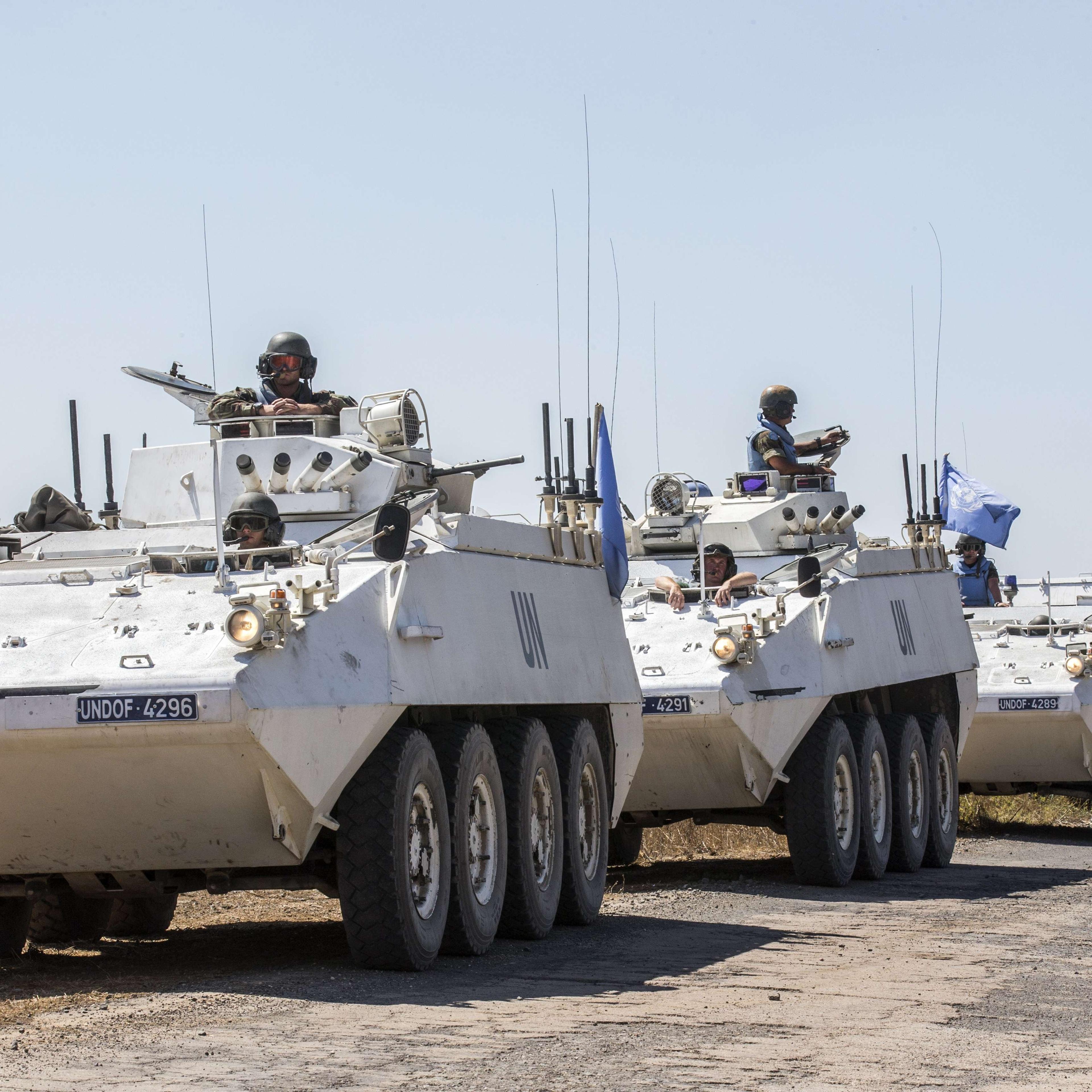 Irish members of the United Nations Disengagement Observer Force (UNDOF) sit on their armoured vehicles in the Israeli-annexed Golan Heights as they wait to cross into the Syrian-controlled territory, on August 28, 2014.