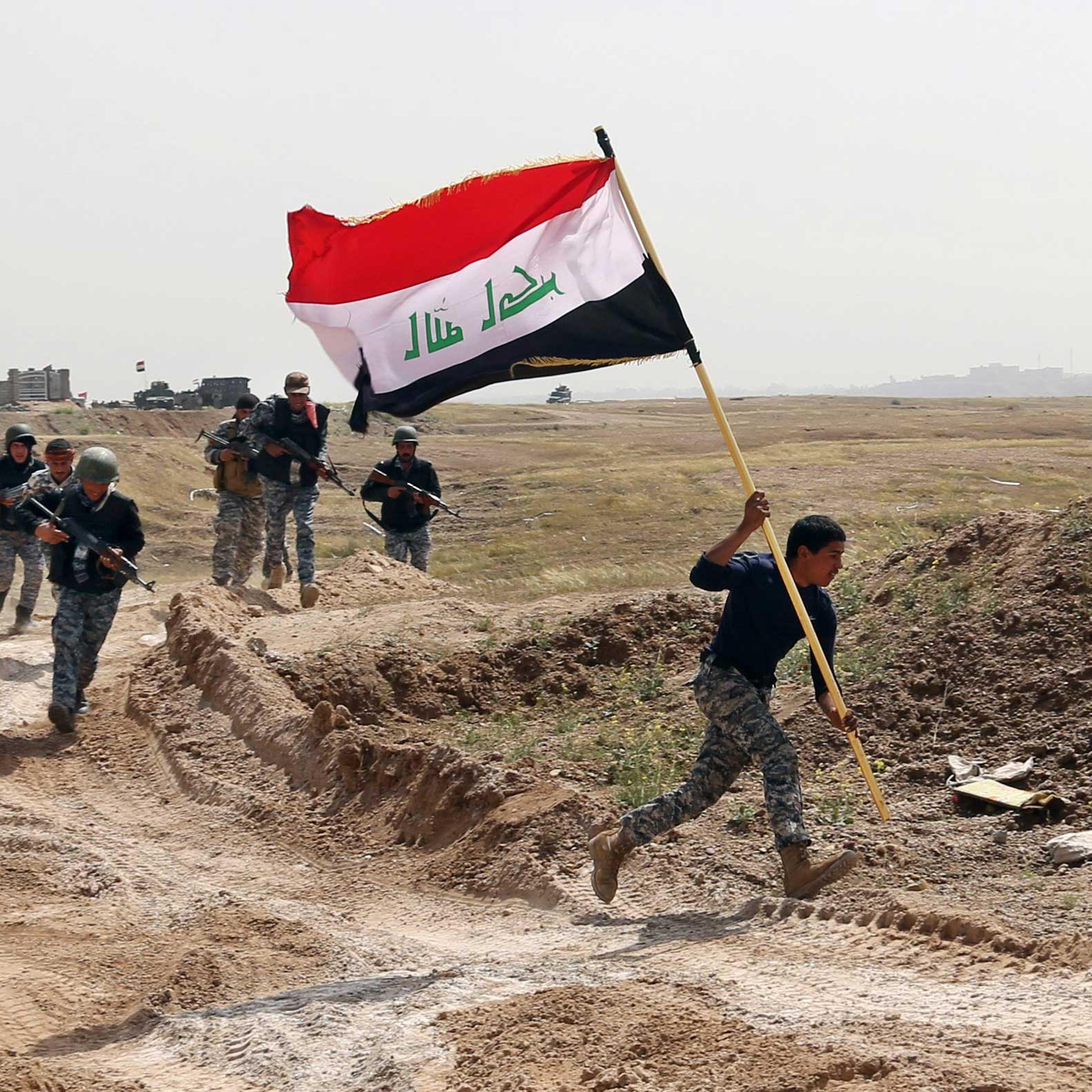 A member of the Iraqi security forces runs to plant the national flag as they surround Tikrit during clashes to regain the city from Islamic State militants, 80 miles north of Baghdad, Iraq, March 30, 2015.