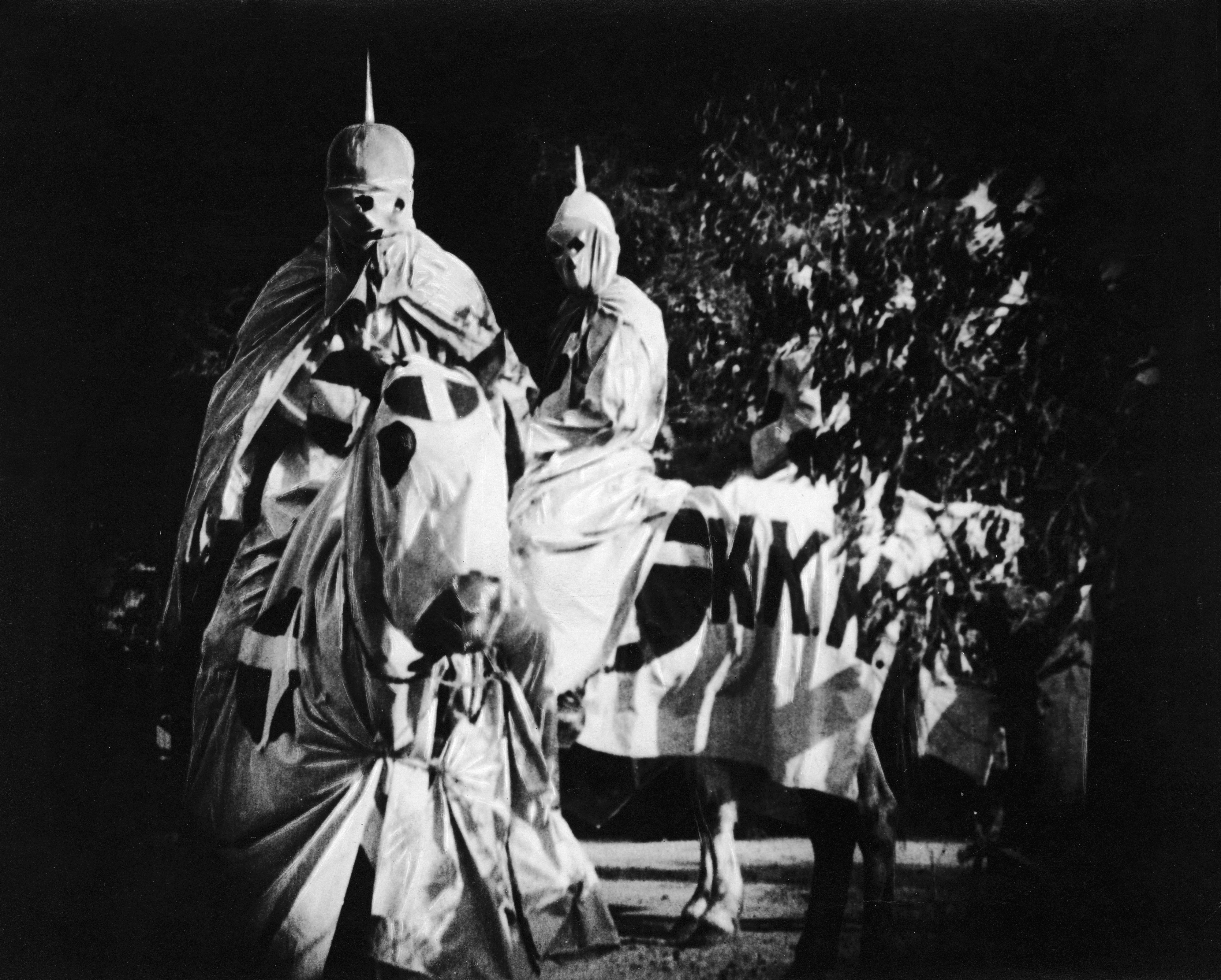 Actors costumed in the full regalia of the Ku Klux Klan ride on horses at night in a still from the 'The Birth of a Nation,' directed by D. W. Griffith, California, 1914.
