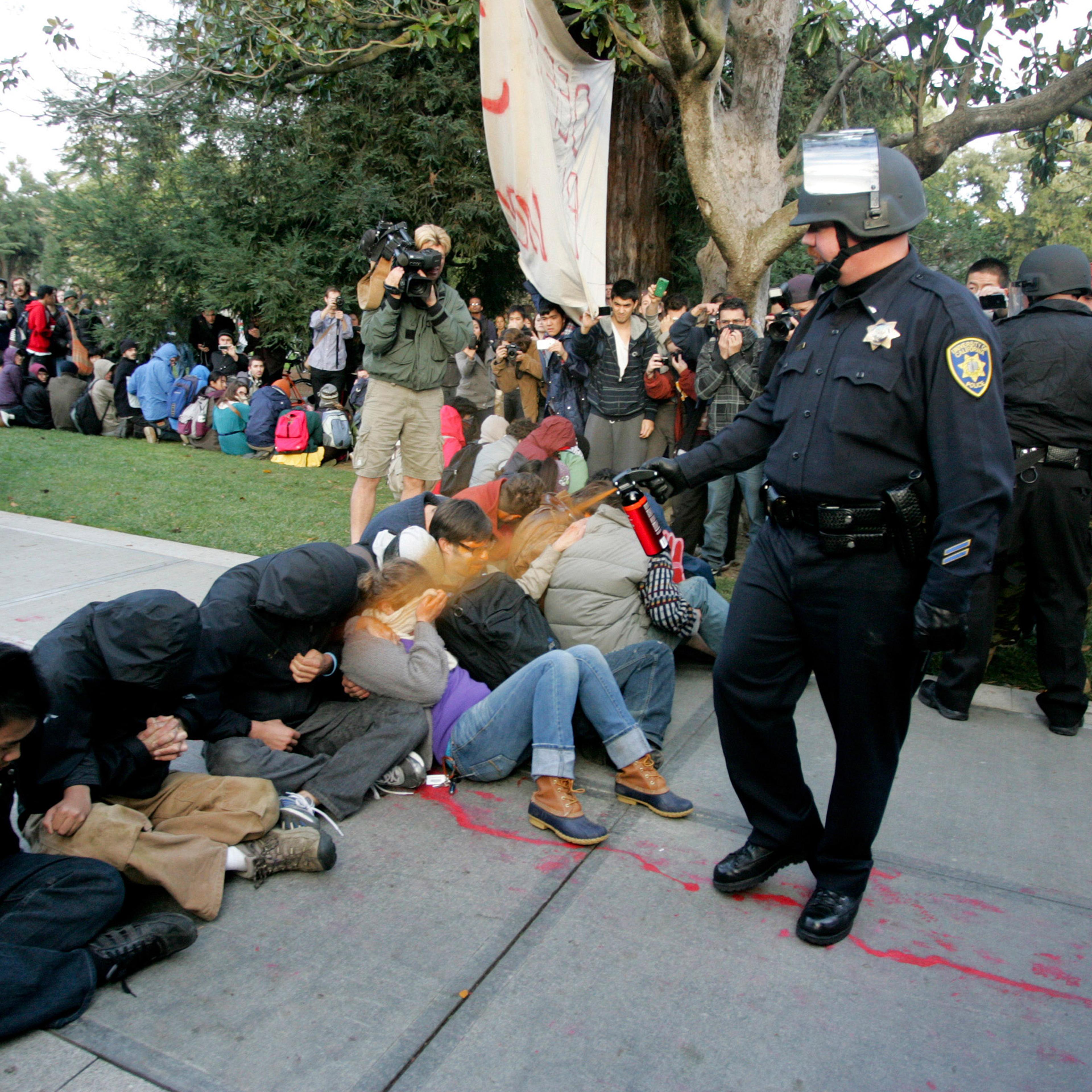 A University of California Davis police officer pepper-sprays students during their sit-in at an "Occupy UCD" demonstration in Davis
