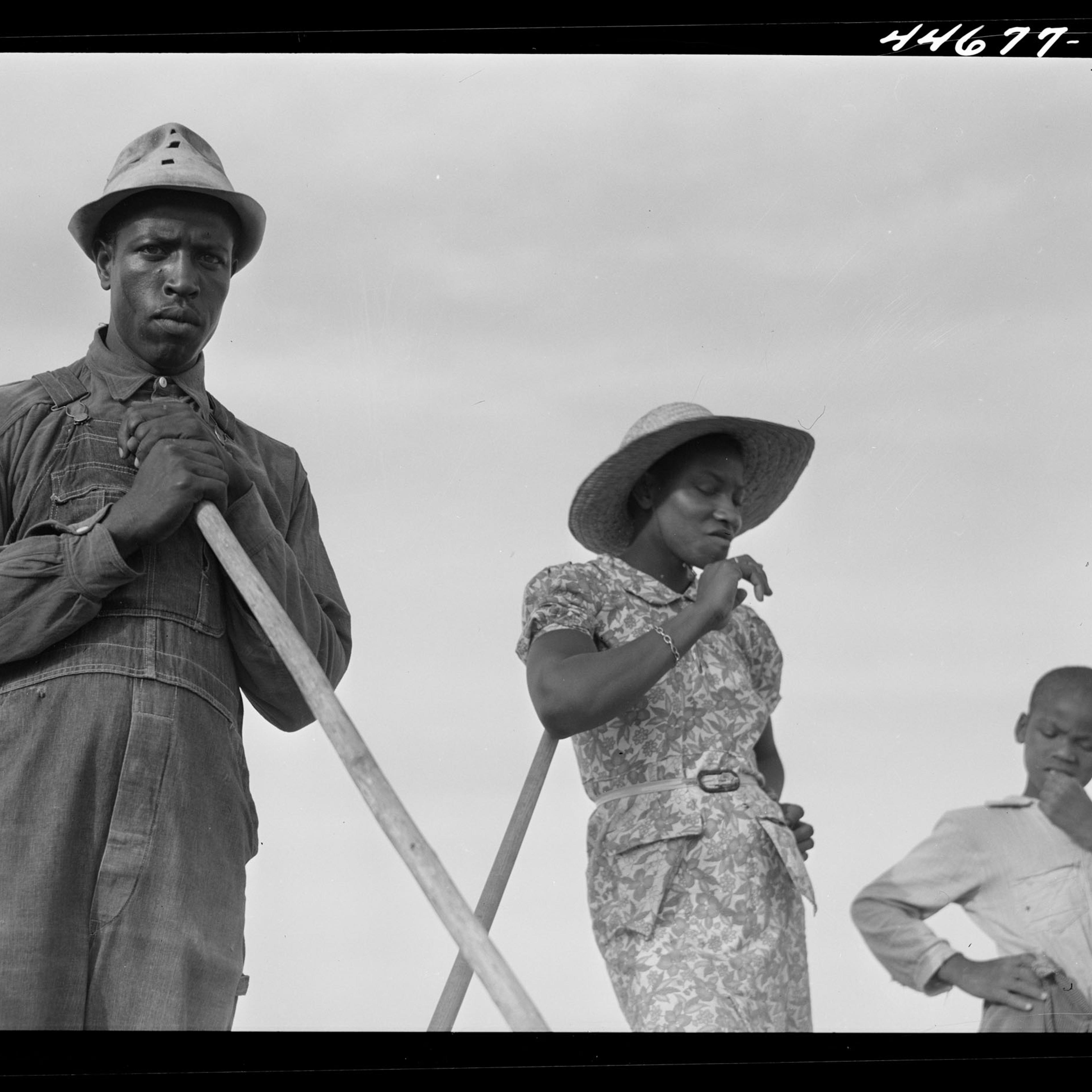 Black farmers standing and a cloudy sky in the background.