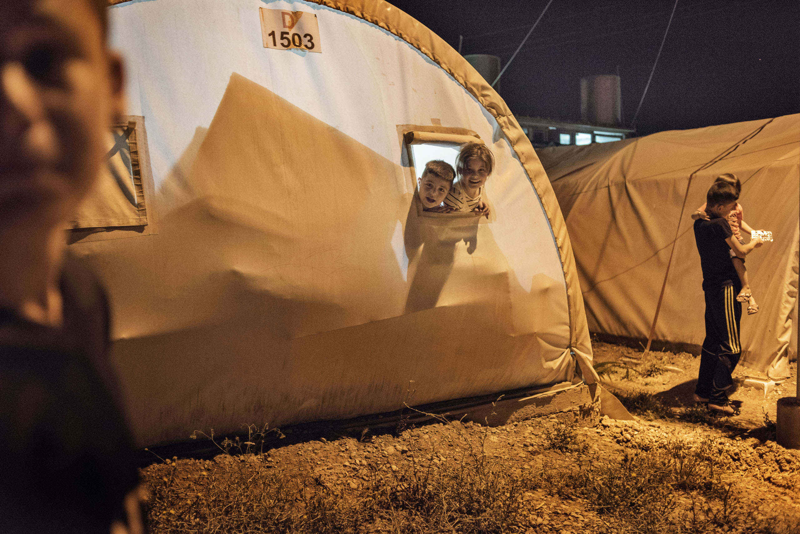 Children peer from a window in a tent in a camp for internally displaced people (IDP's) outside the city of Dohuk, in Iraq's autonomous Kurdish region, May 19, 2016.
