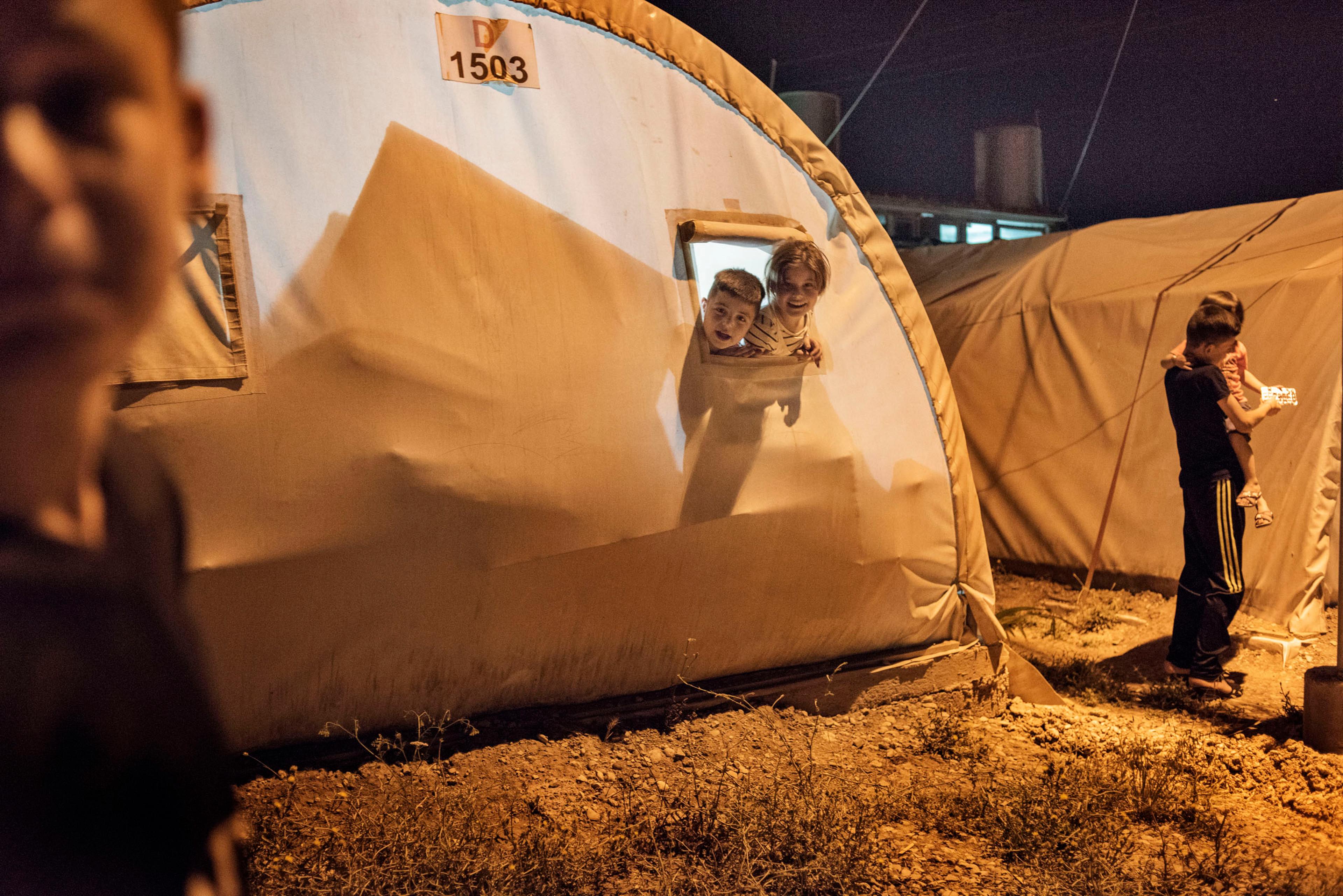 Children peer from a window in a tent in a camp for internally displaced people (IDP's) outside the city of Dohuk, in Iraq's autonomous Kurdish region, May 19, 2016.