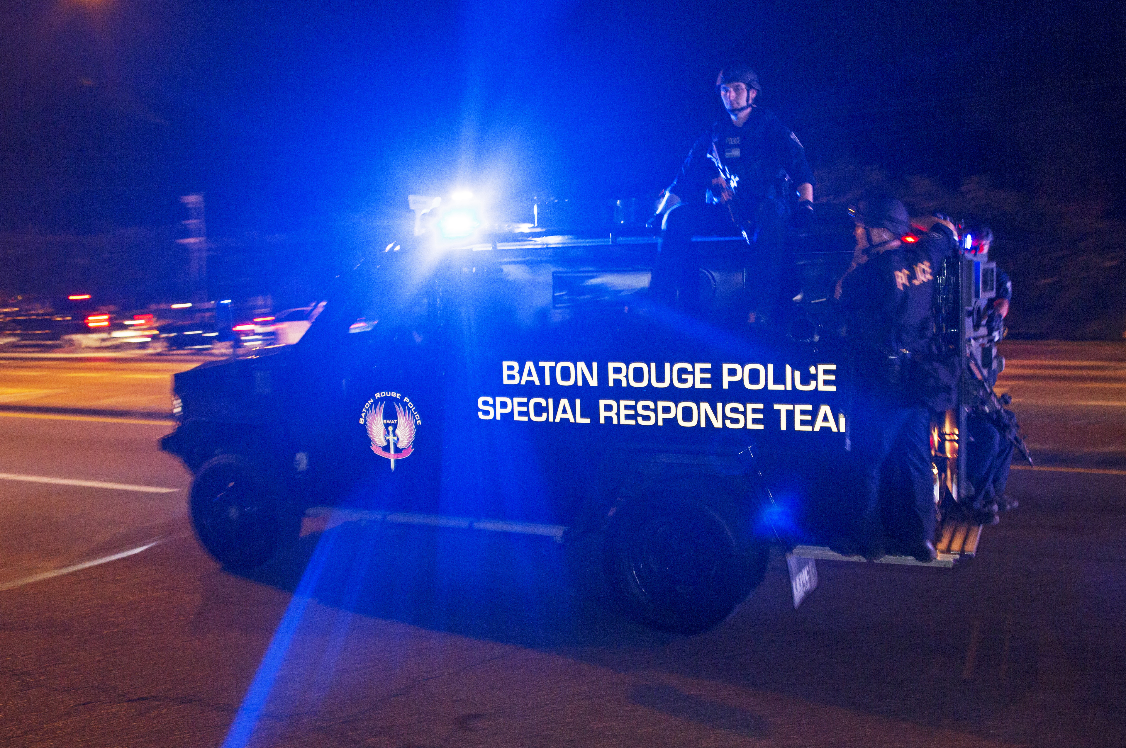 Sheriff deputies ride outside an armored vehicle in Baton Rouge, La., on July 9, 2016.