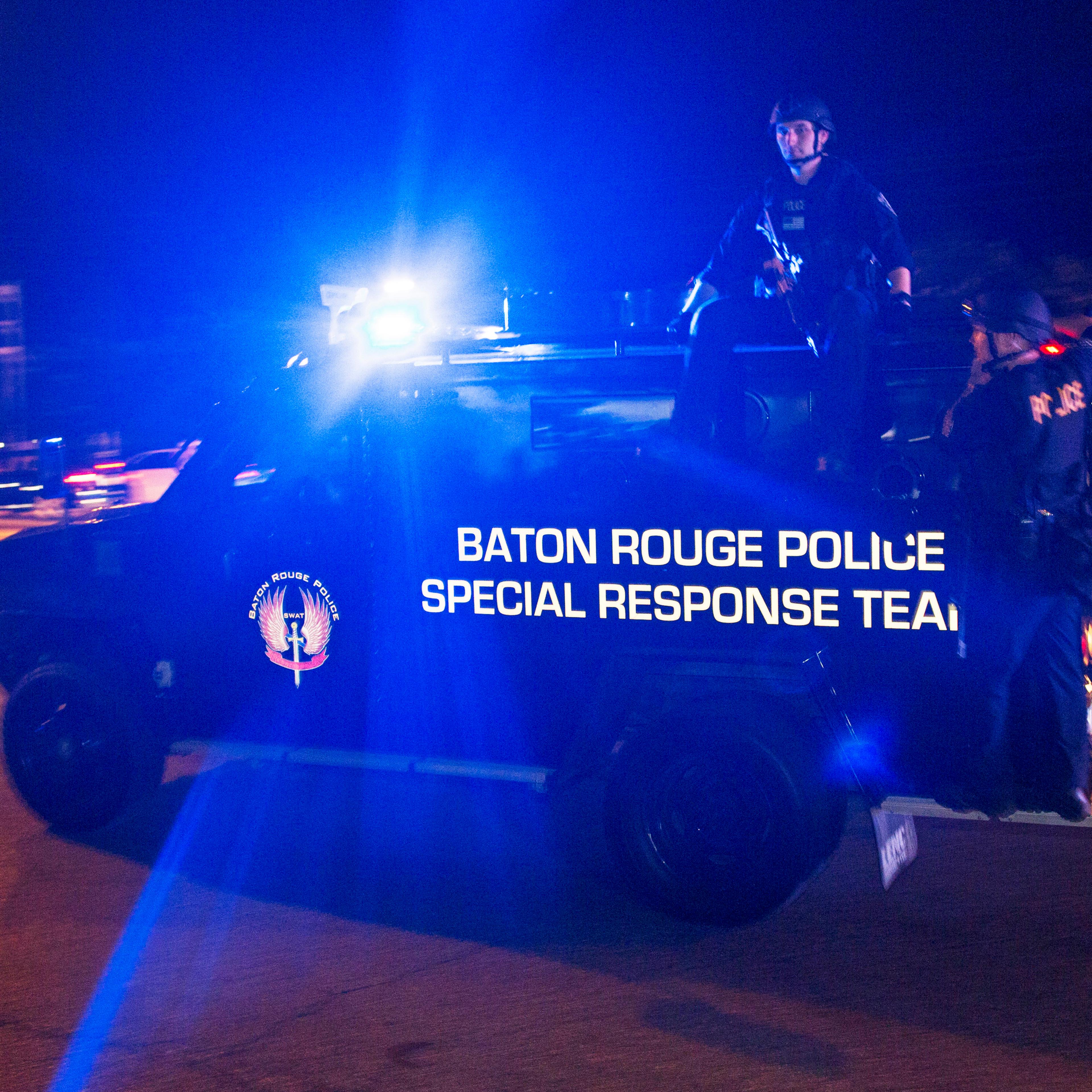 Sheriff deputies ride outside an armored vehicle in Baton Rouge, La., on July 9, 2016.