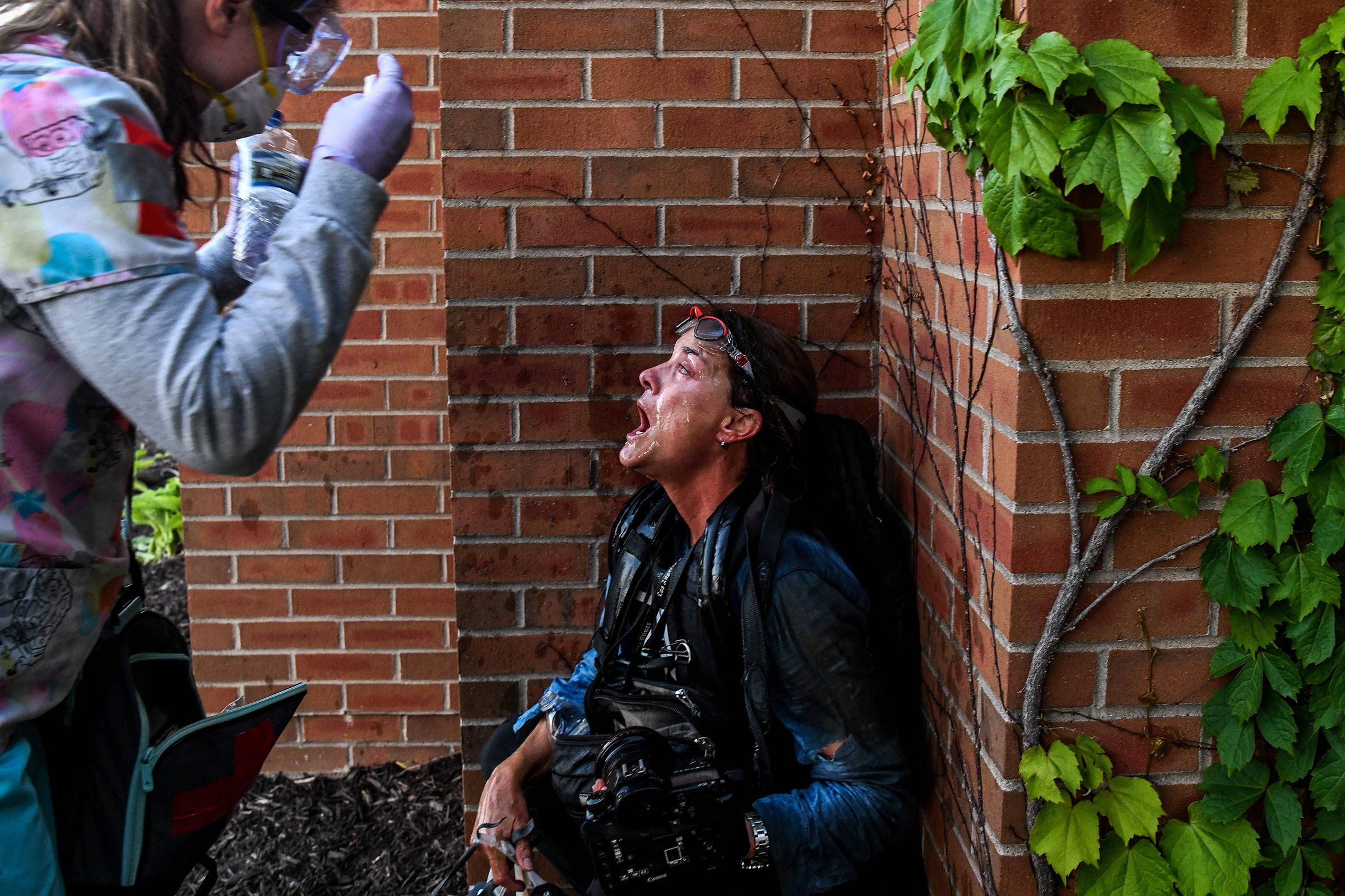 A medic protestor assists a member of the media after police started firing tear gas and rubber bullets near the 5th police precinct during a demonstration to call for justice for George Floyd on May 30, 2020 in Minneapolis, Minnesota.