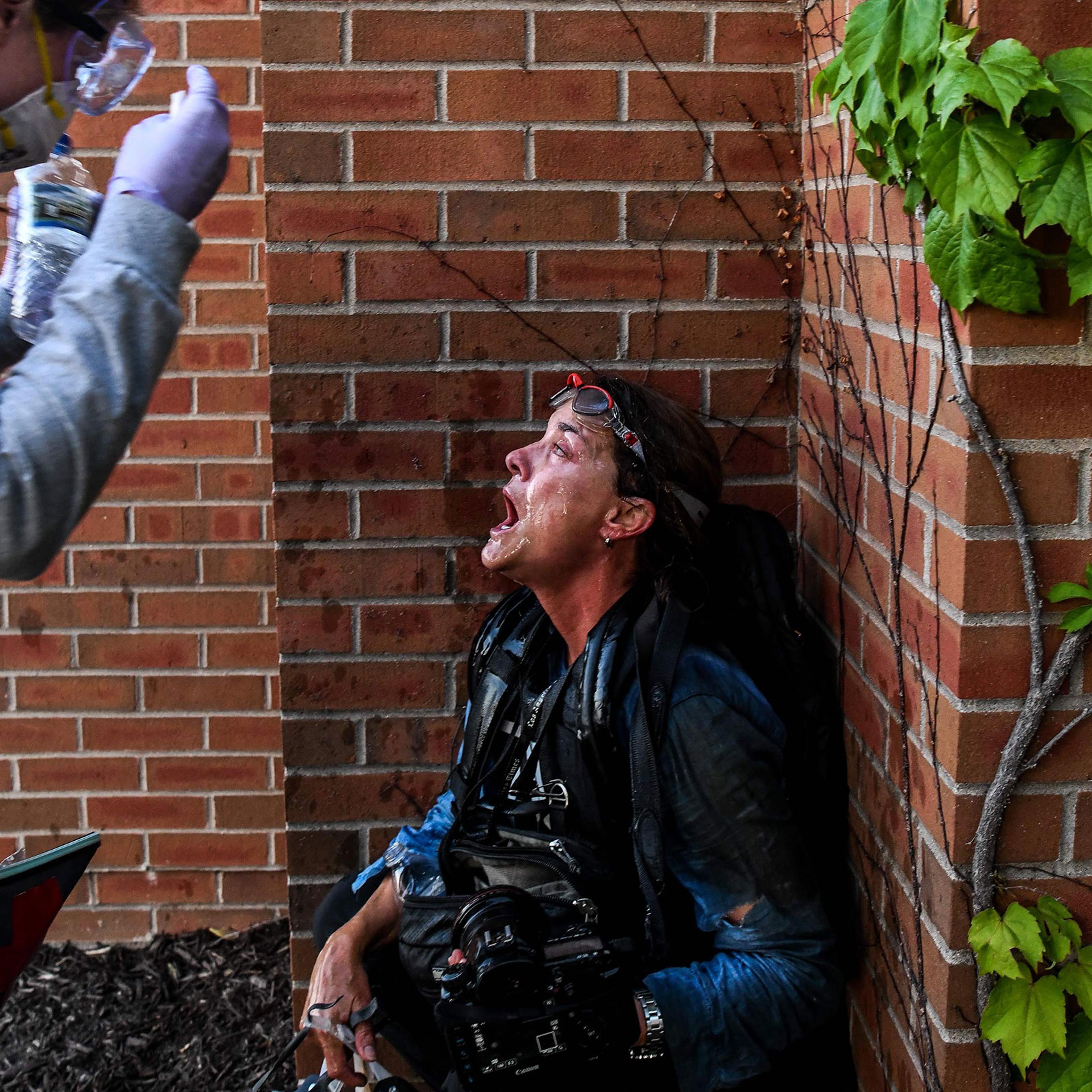 A medic protestor assists a member of the media after police started firing tear gas and rubber bullets near the 5th police precinct during a demonstration to call for justice for George Floyd on May 30, 2020 in Minneapolis, Minnesota.