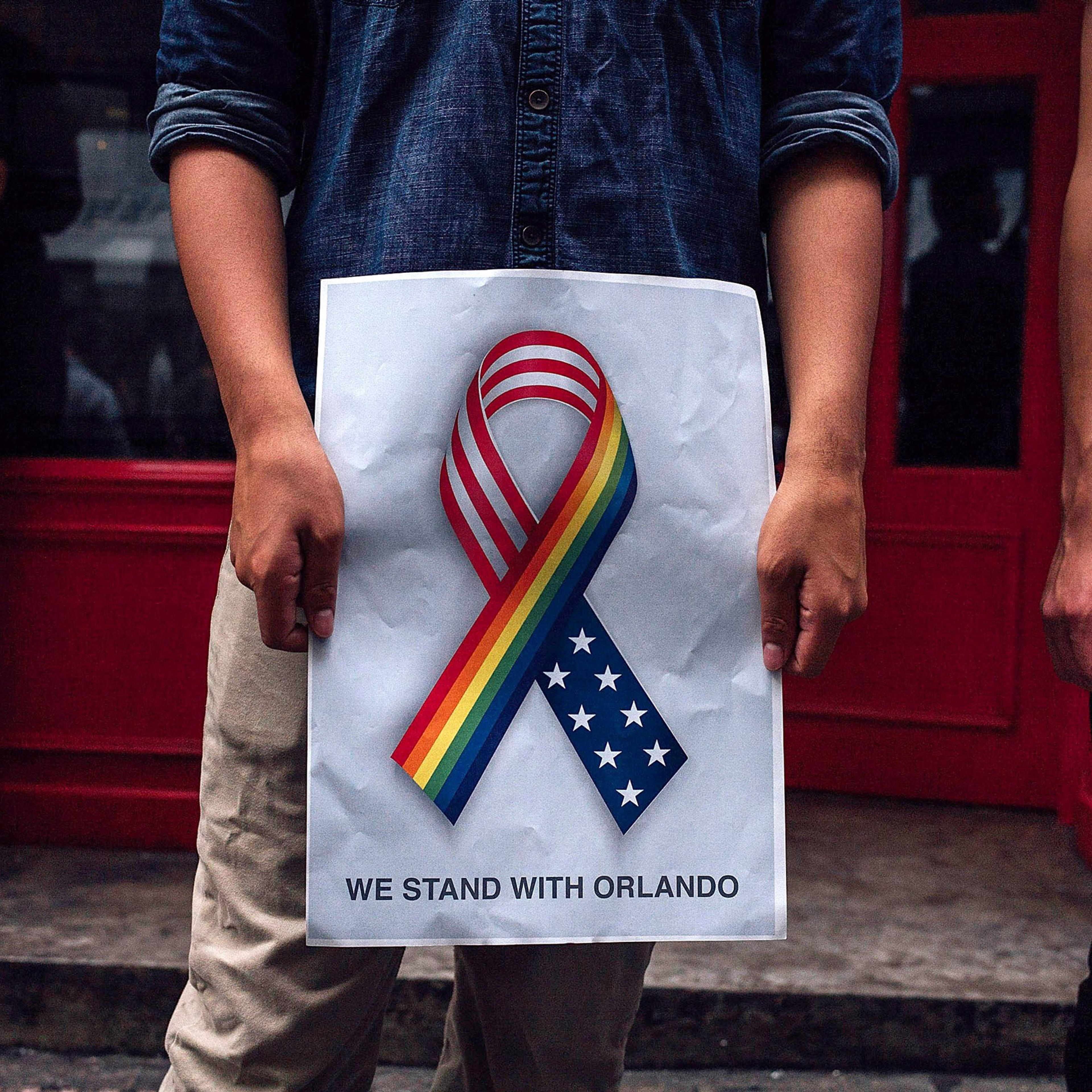 HONG KONG - JUNE 13: A man holds up a 'we stand together with Orlando' poster as people take part in a candlelight vigil for the victims of a shooting in a gay nightclub in Orlando, Florida on June 13, 2016 in Hong Kong, Hong Kong. The vigil is put toget