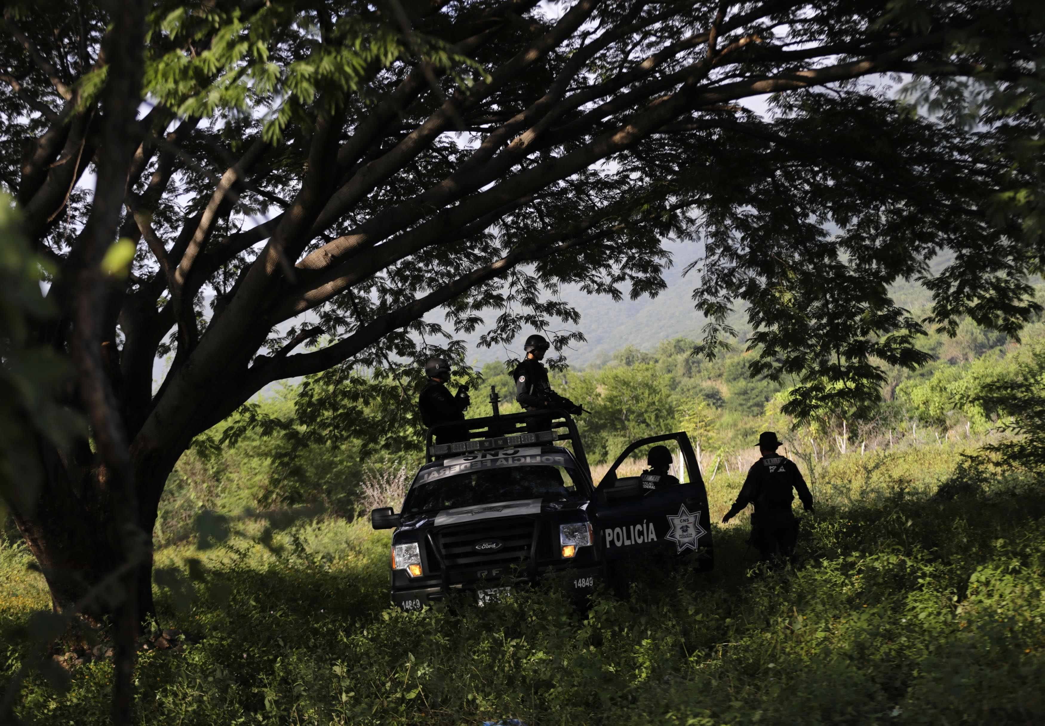 Federal police atop a vehicle stand guard near clandestine graves at Pueblo Viejo