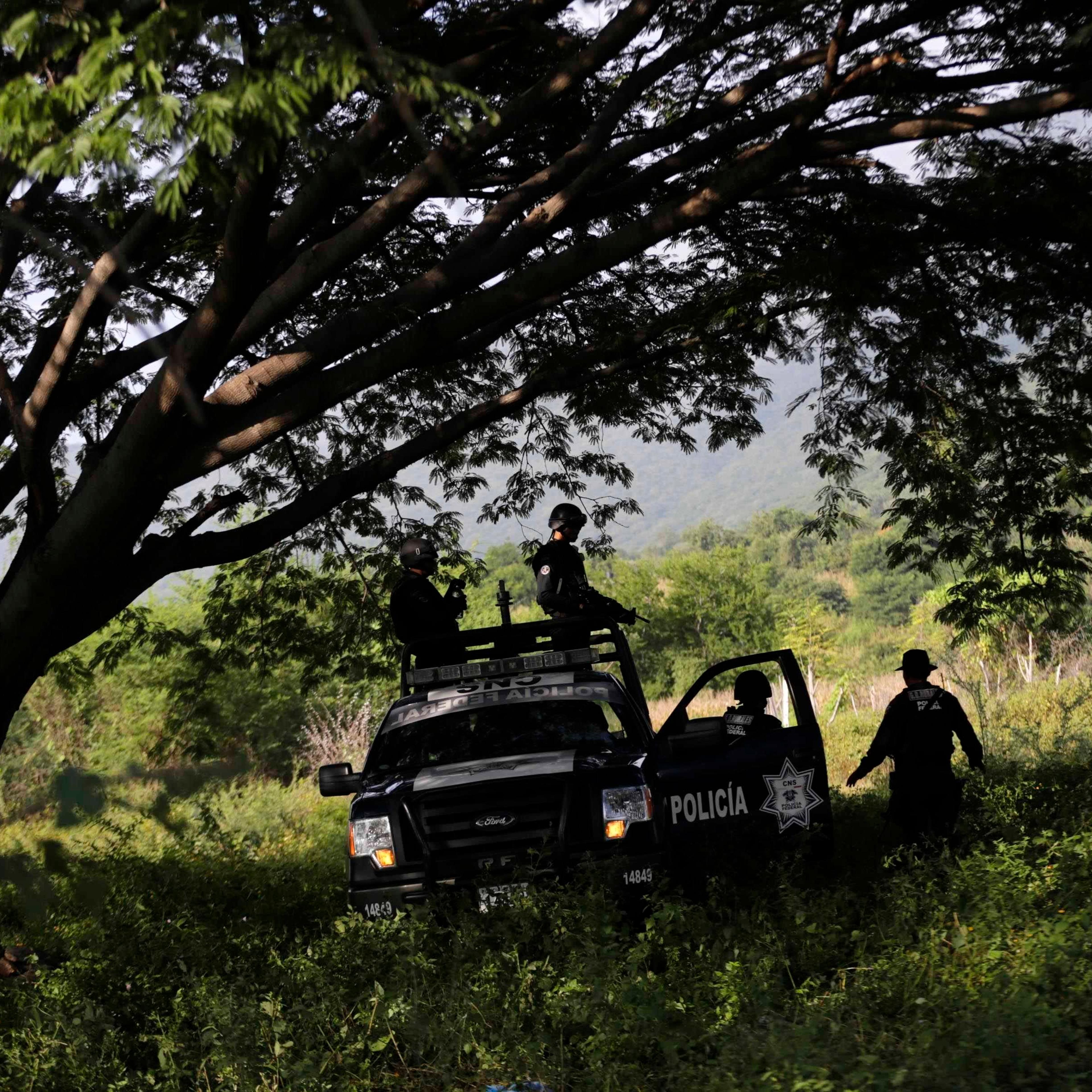 Federal police atop a vehicle stand guard near clandestine graves at Pueblo Viejo