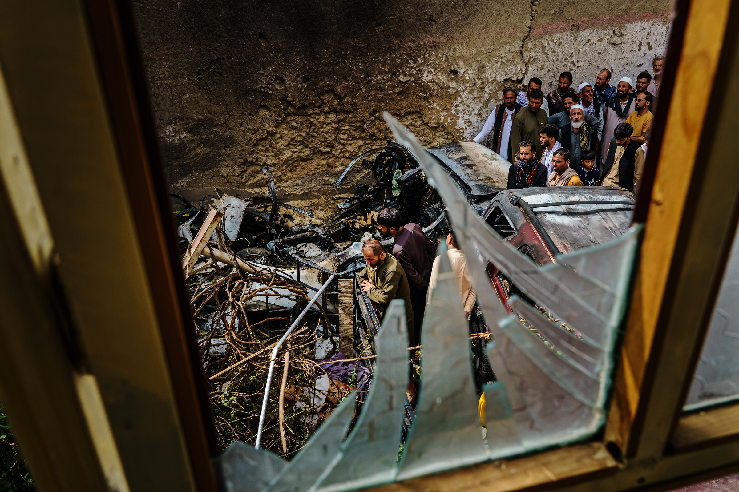 Relatives and neighbors of the Ahmadi family gathered around the incinerated husk of a vehicle, targeted a day earlier by an American drone strike, in Kabul on Aug. 30, 2021. Ten civilians, including seven children, were killed.