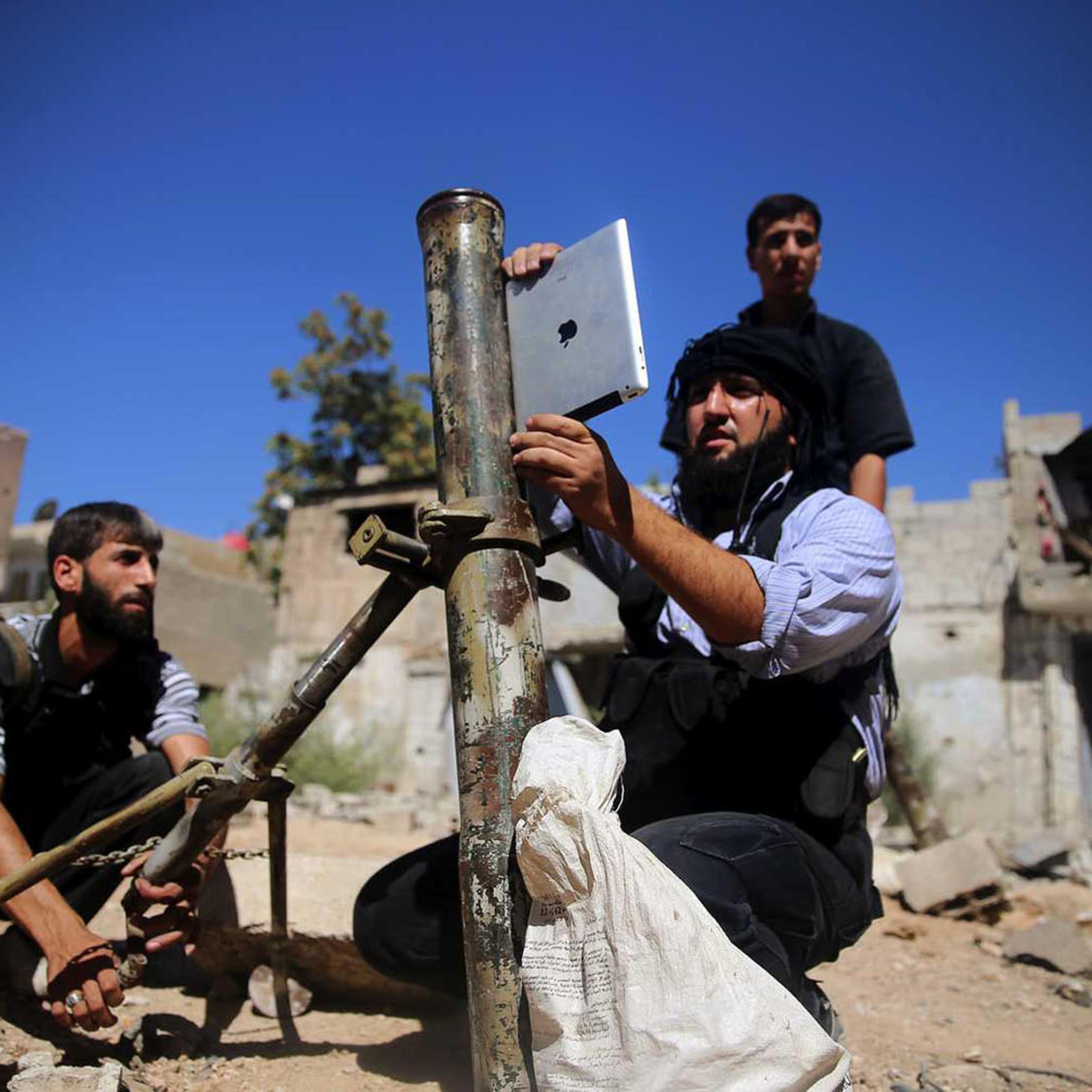 A rebel fighter, who belongs to the Free Syrian Army, uses an iPad during preparations to fire a homemade mortar at a battlefront in Damascus on Sept. 15, 2013
