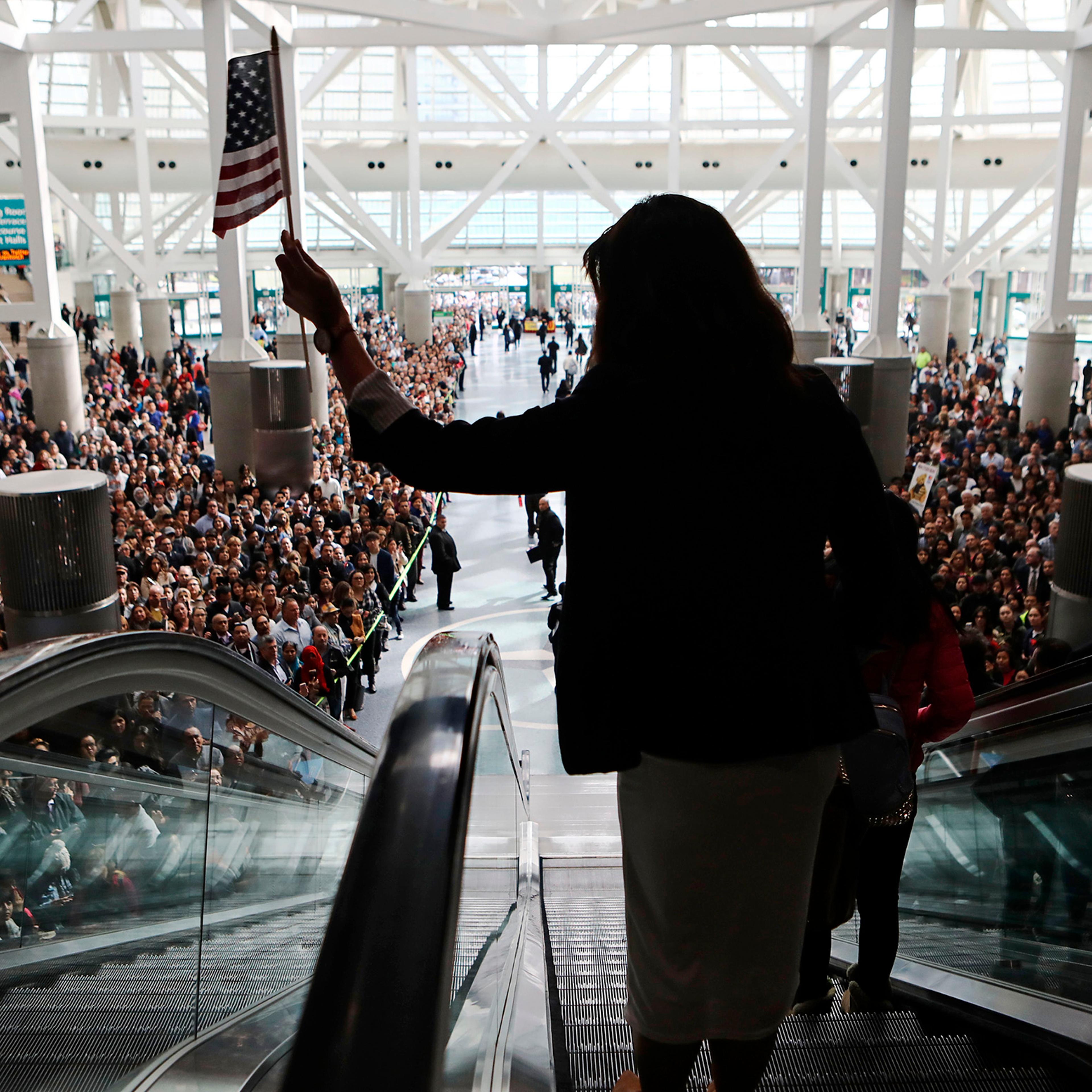 A new U.S. citizen, leaving a 2018 mass naturalization ceremony in L.A., waves the flag