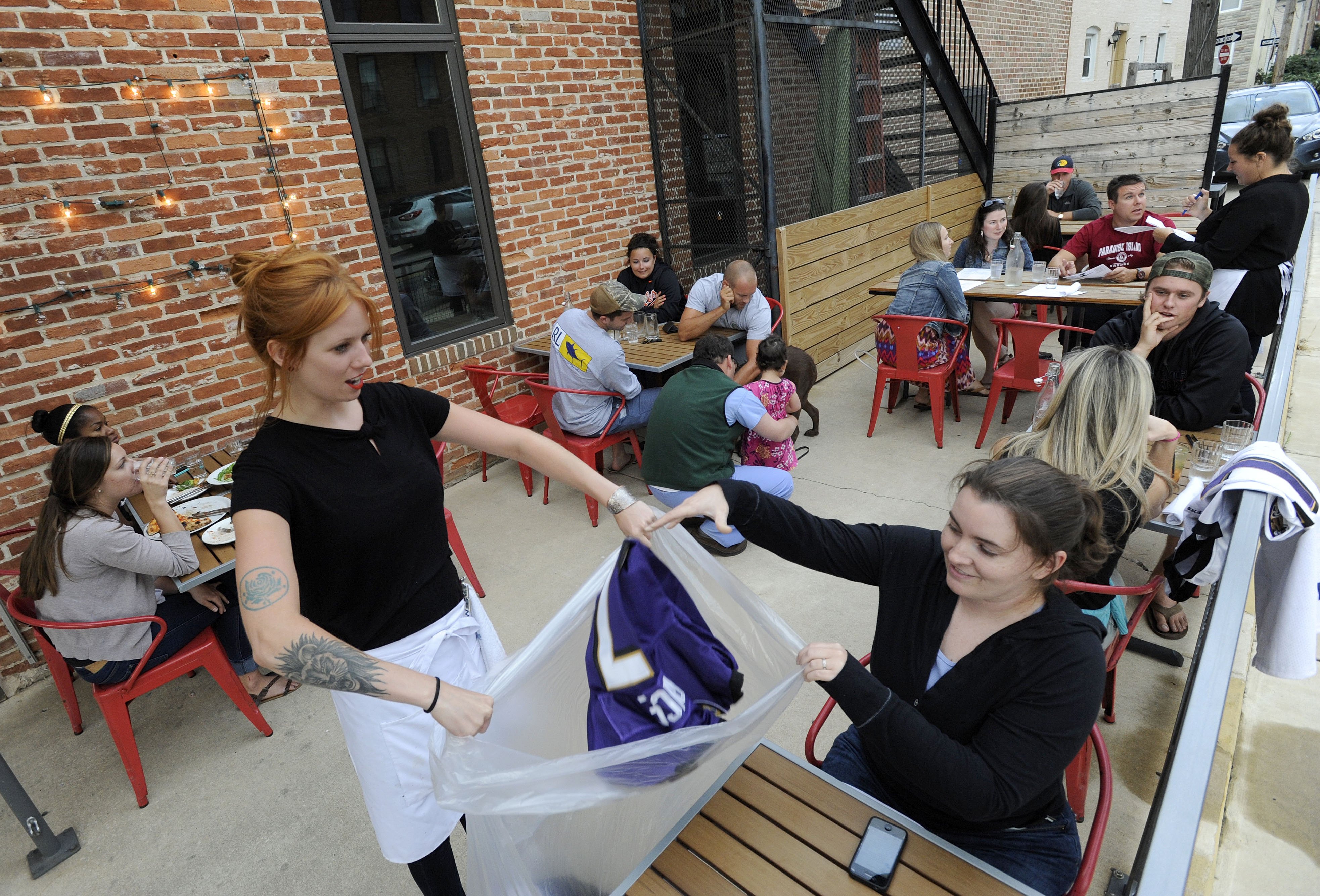 Bartender Abby Hopper, left, of Baltimore, collects a Ray Rice Baltimore Ravens football jersey from Erin McGonigle, right, of Arbutus, Md., at Hersh's Pizza and Drinks, a Baltimore restaurant that offered a free personal pizza in exchange for Rice jerse