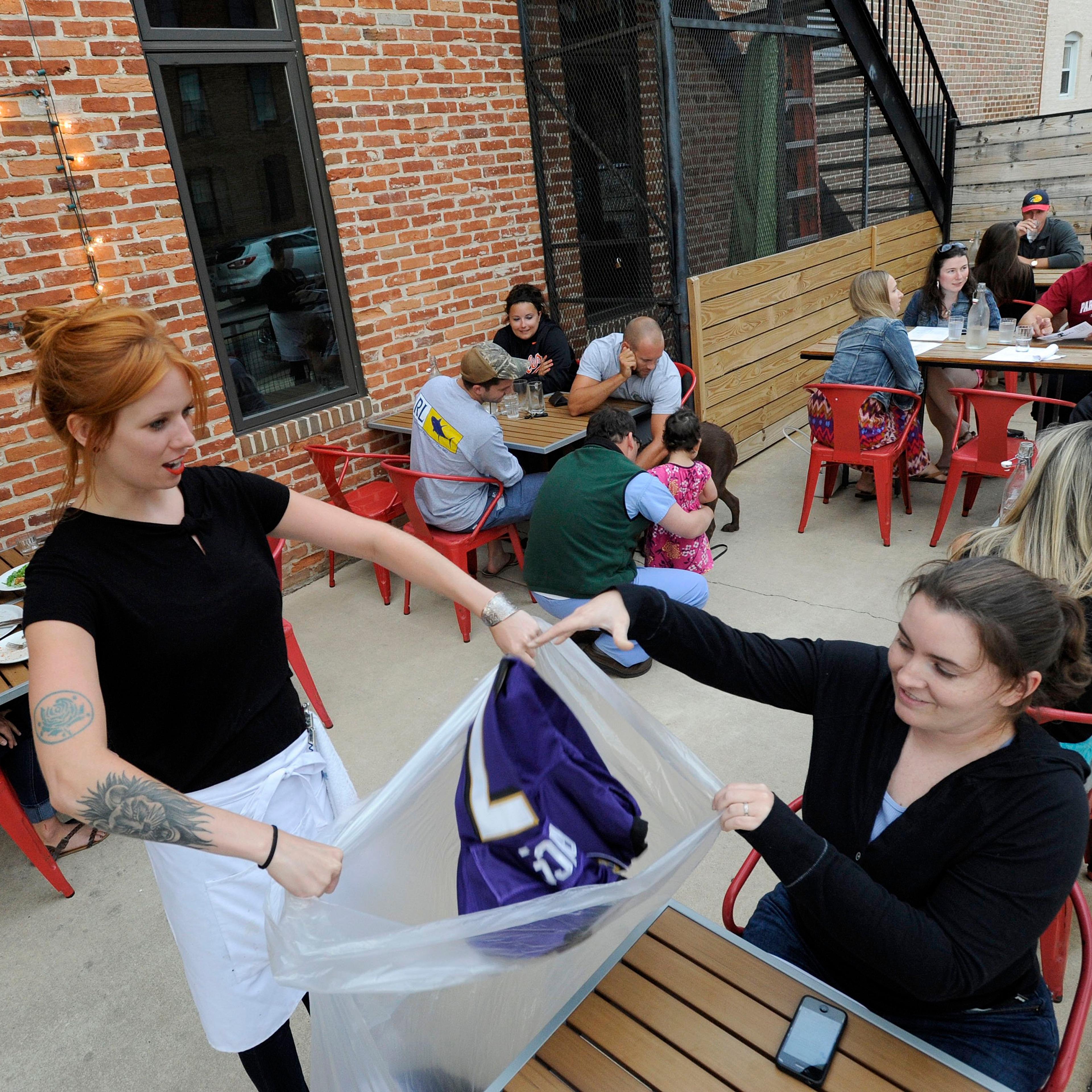 Bartender Abby Hopper, left, of Baltimore, collects a Ray Rice Baltimore Ravens football jersey from Erin McGonigle, right, of Arbutus, Md., at Hersh's Pizza and Drinks, a Baltimore restaurant that offered a free personal pizza in exchange for Rice jerse