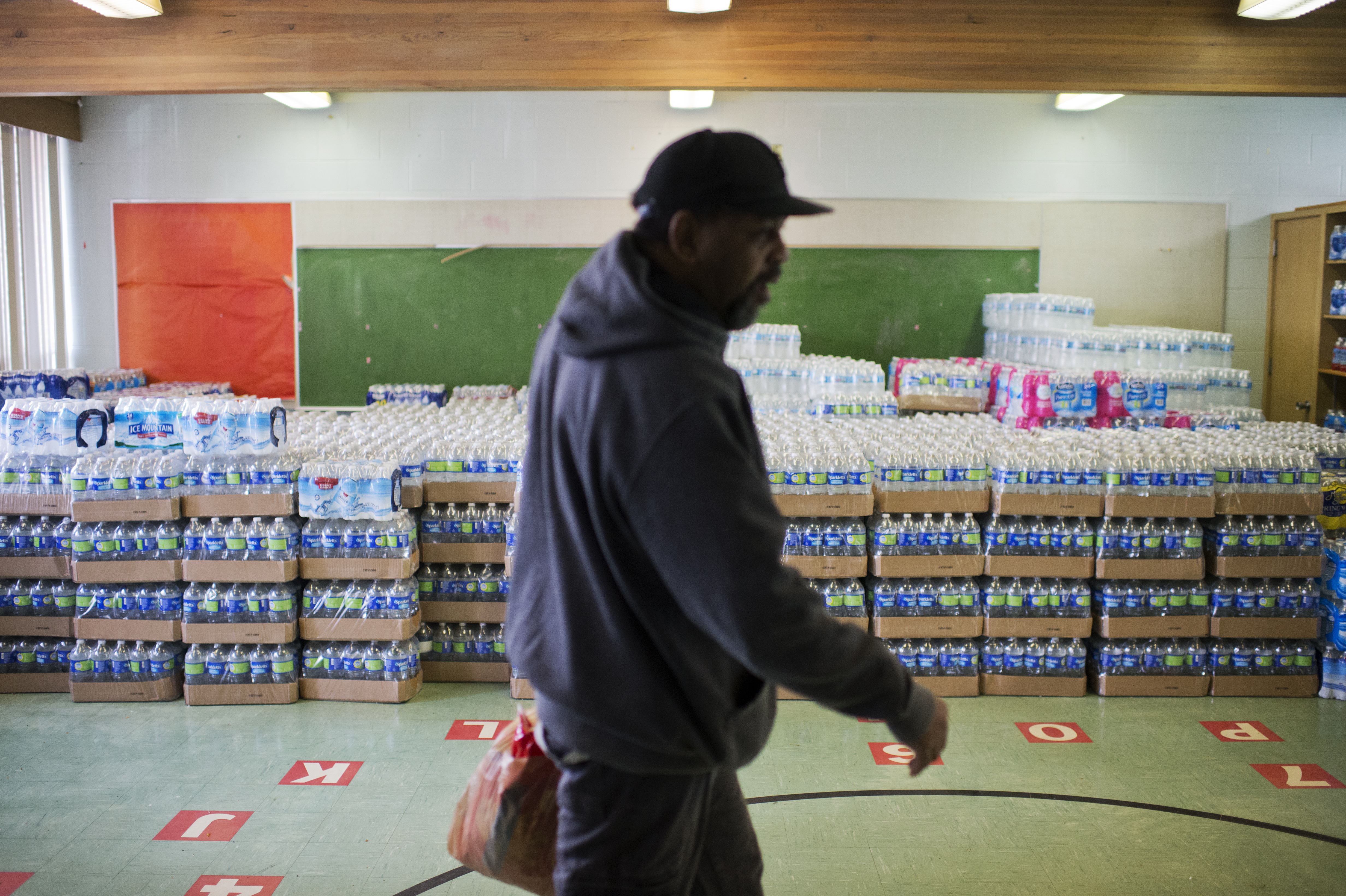 UNITED STATES - FEBRUARY 23: A volunteer walks by cases of bottled water at the St. Mark Baptist Church in Flint, Mich., that serves as a water distribution area, February 23, 2016. The water supply was not properly treated after being switched from Lake