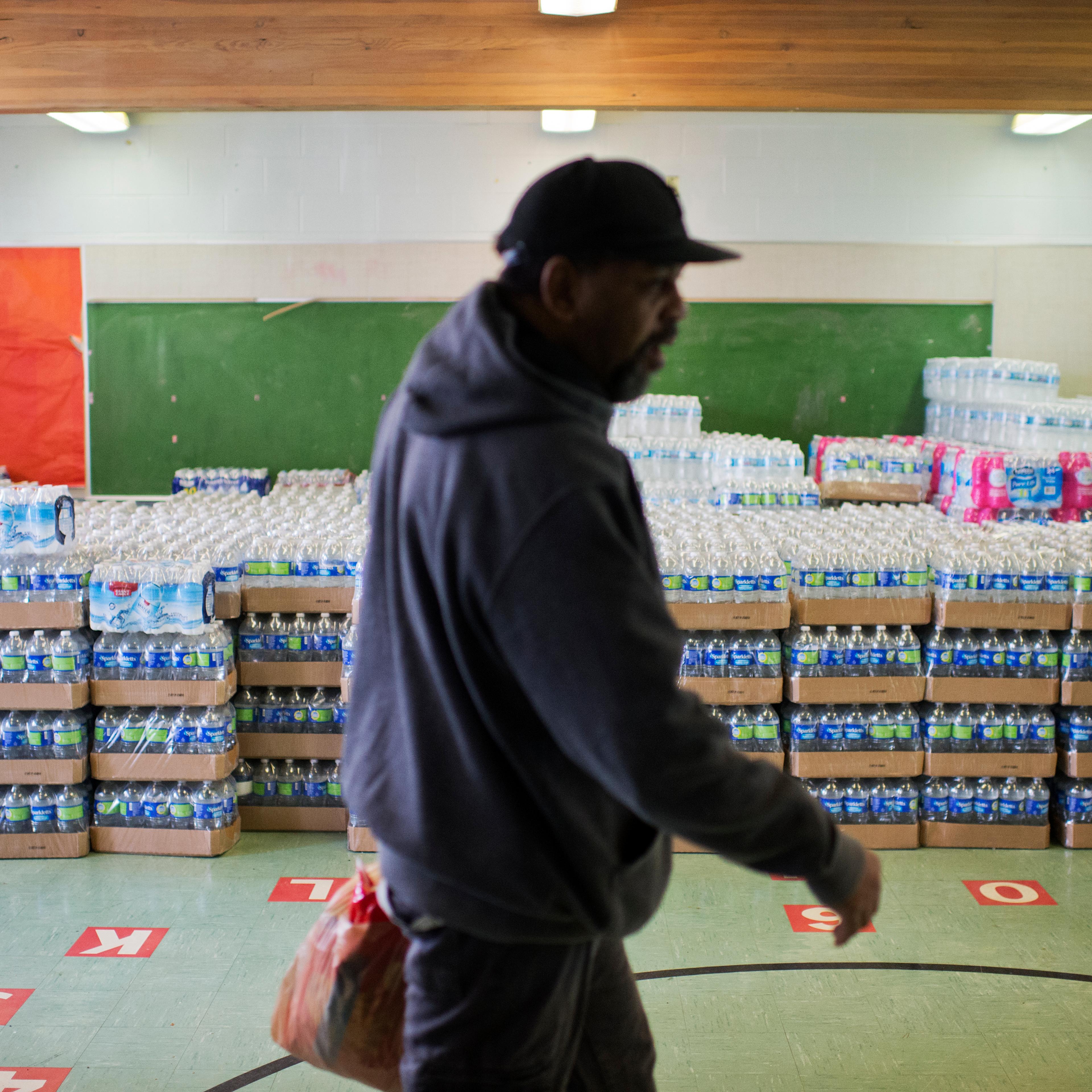 UNITED STATES - FEBRUARY 23: A volunteer walks by cases of bottled water at the St. Mark Baptist Church in Flint, Mich., that serves as a water distribution area, February 23, 2016. The water supply was not properly treated after being switched from Lake