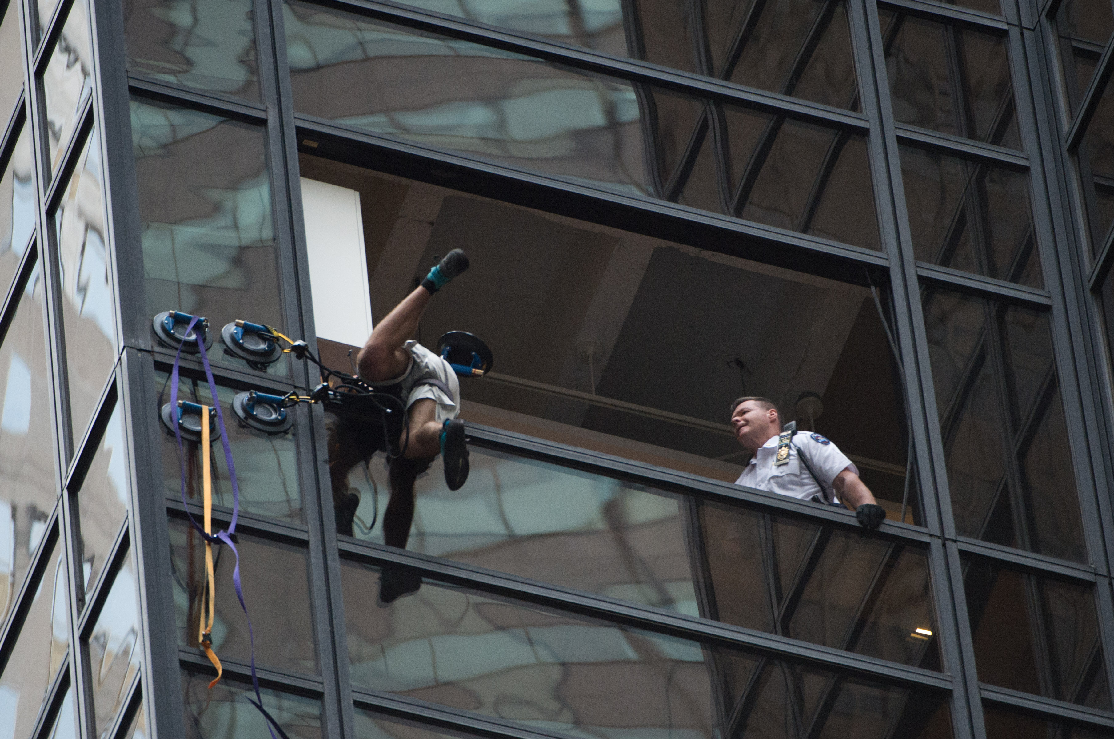 Police grab an unidentified man scaling Trump Tower using suction cups, August 10, 2016 in New York. Police on August 10, 2016 captured a climber scaling Trump Tower, dragging him to safety through an open window on the 21st floor of the New York headqua