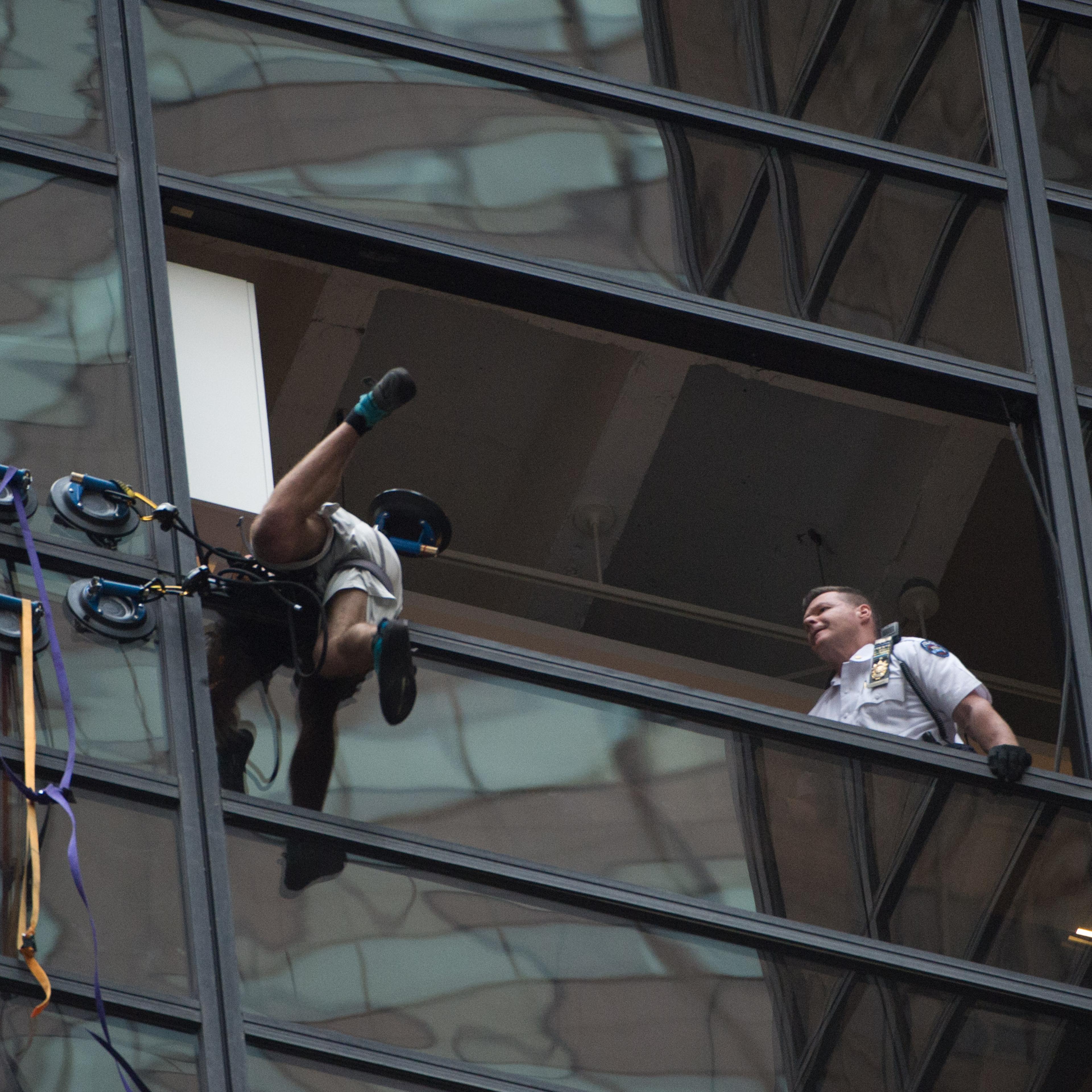 Police grab an unidentified man scaling Trump Tower using suction cups, August 10, 2016 in New York. Police on August 10, 2016 captured a climber scaling Trump Tower, dragging him to safety through an open window on the 21st floor of the New York headqua