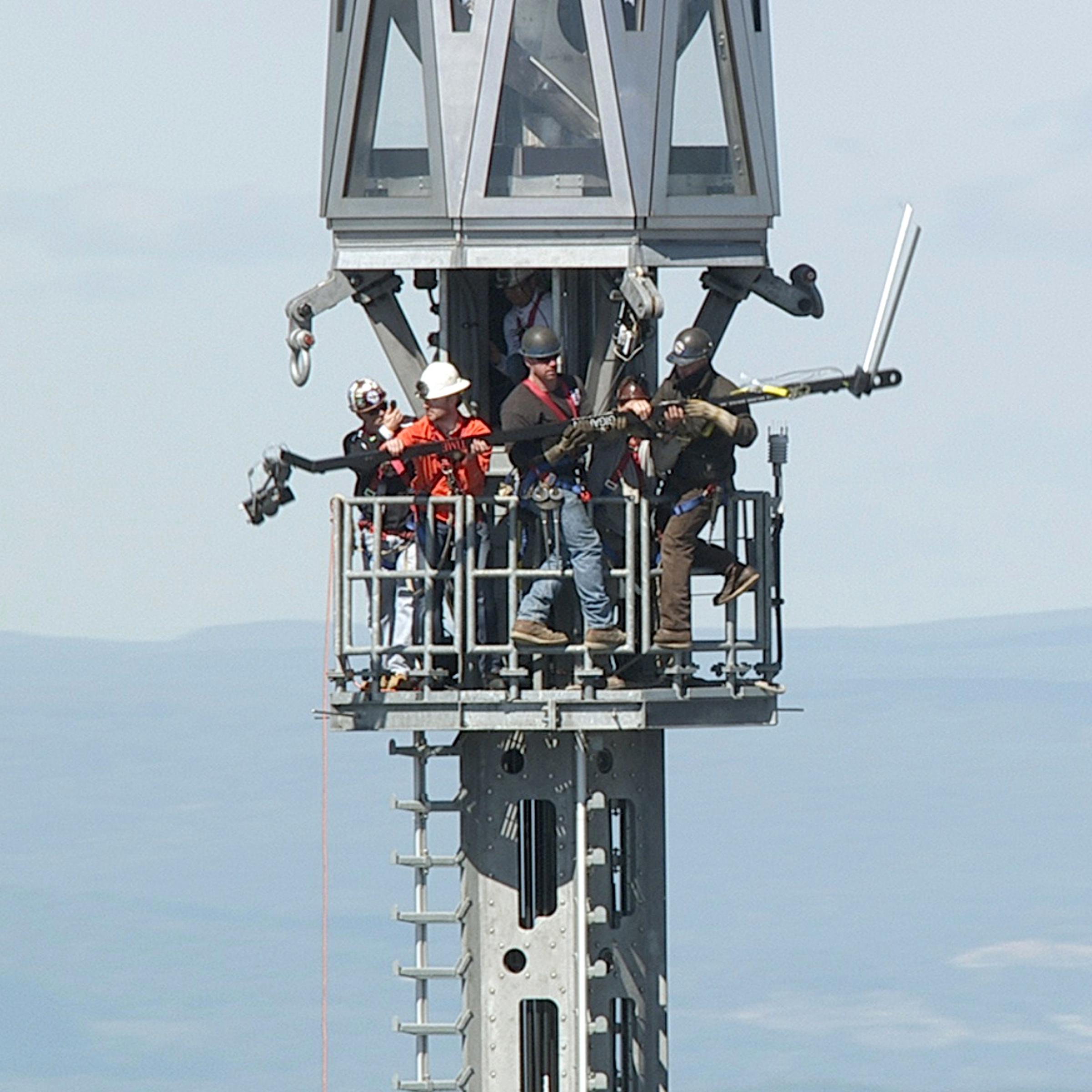 Jonathan Woods (in orange) assists ironworkers as they remove the 13-foot-long jib from the beacon at the very top of 1 World Trade Center in New York City on Sept. 28, 2013.