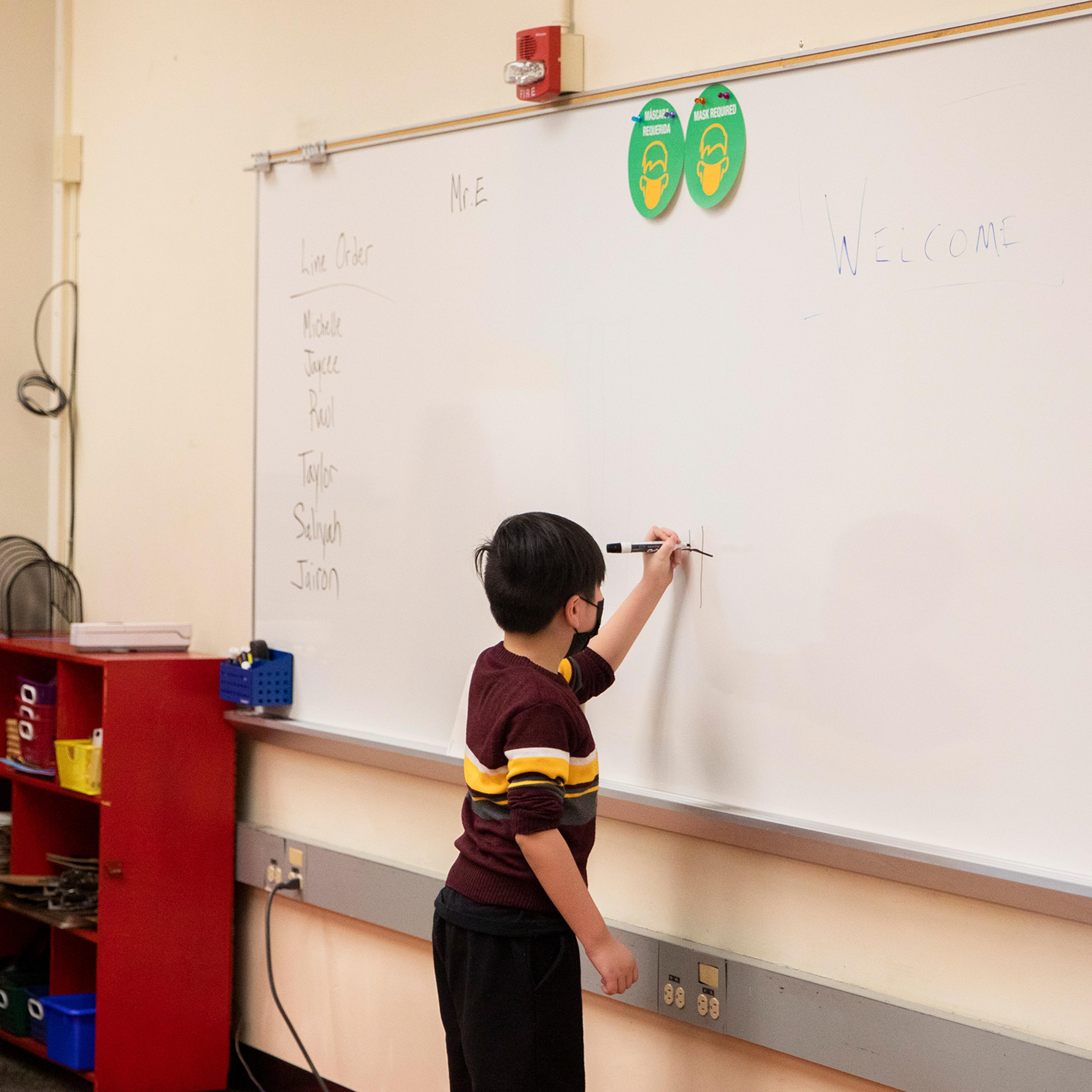 A second-grade student works on a math problem on the board at an elementary school in California.