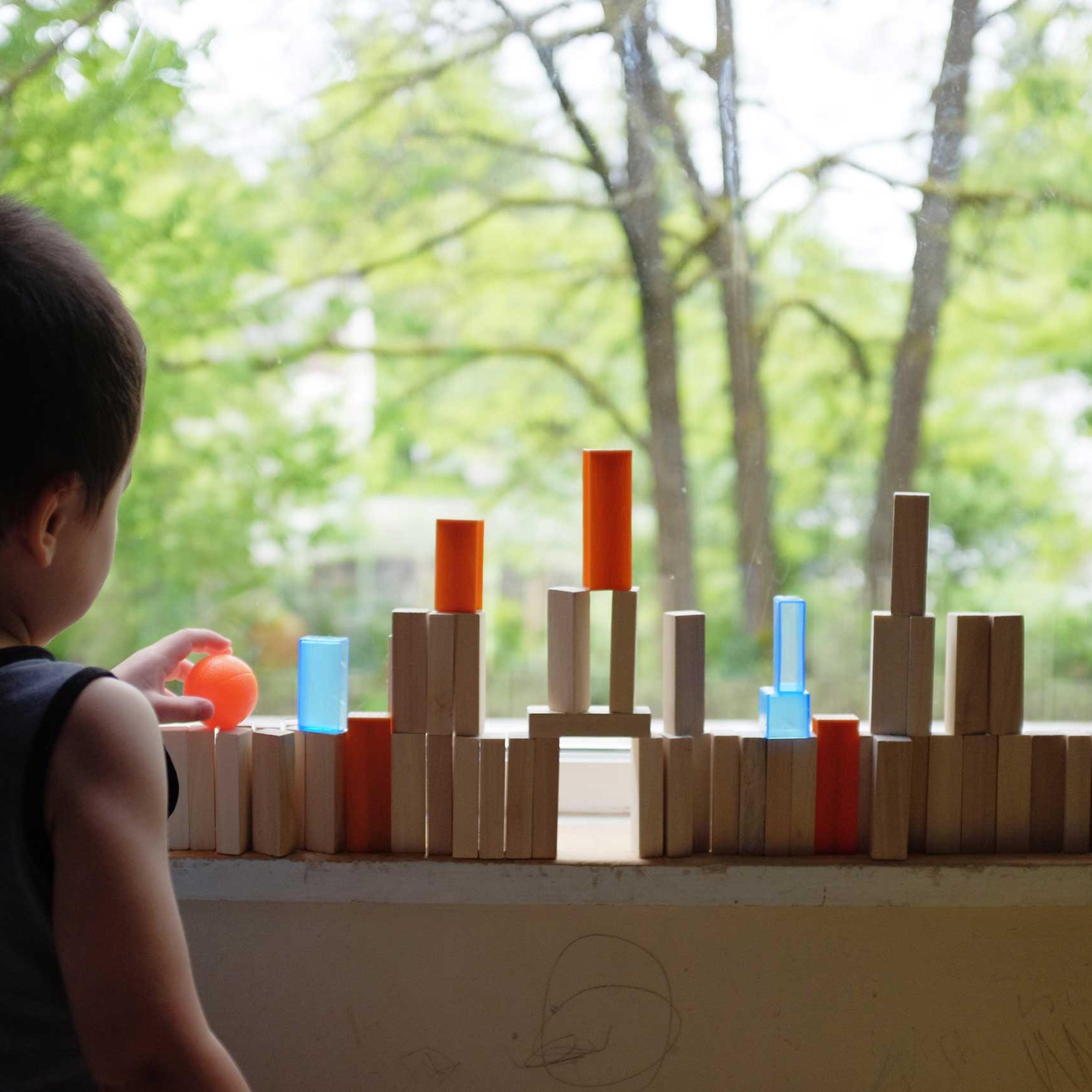Child building tower with blocks on window sill