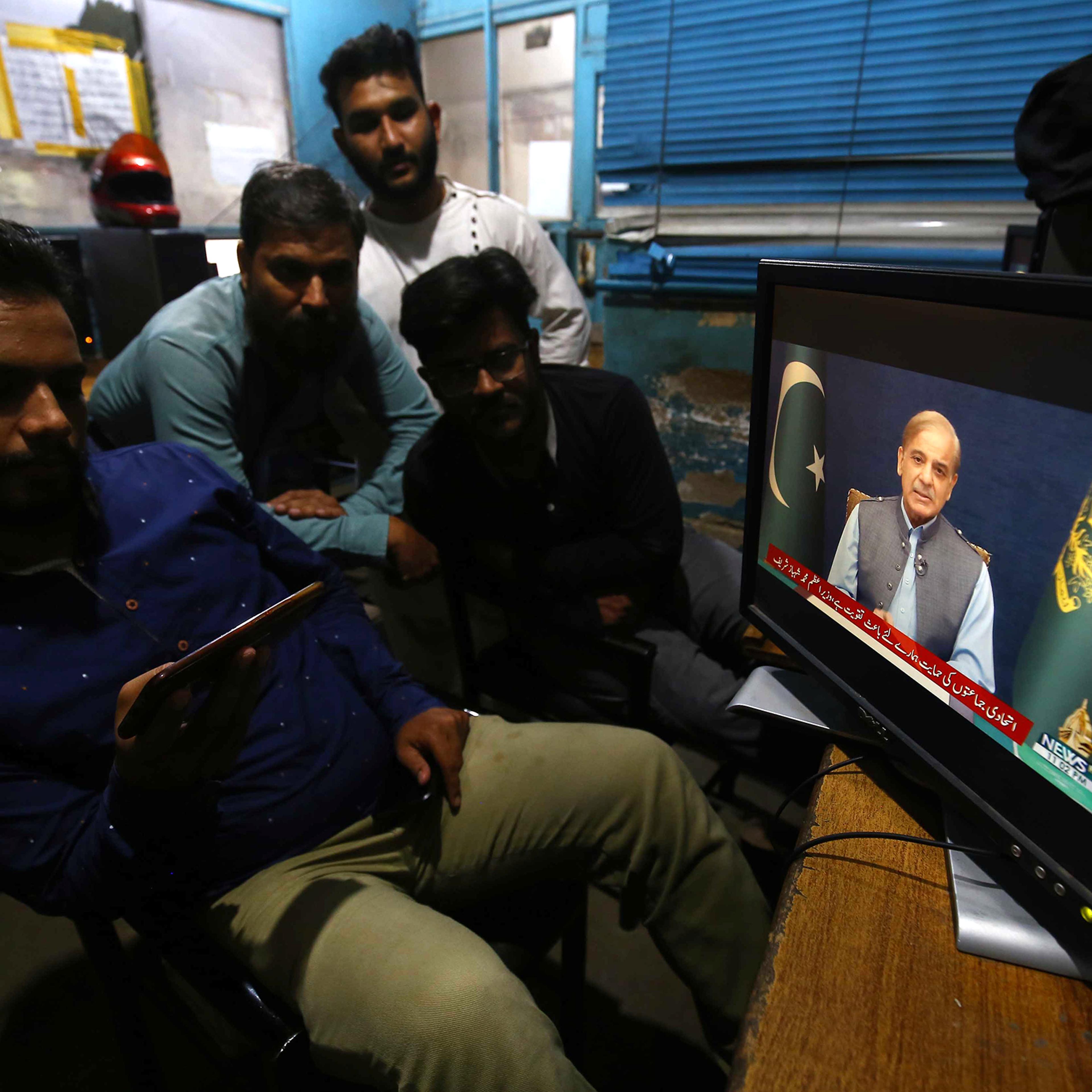 People listen to a televised speech by Pakistani Prime Minister Shehbaz Sharif in Karachi, Pakistan, on May 27, 2022.