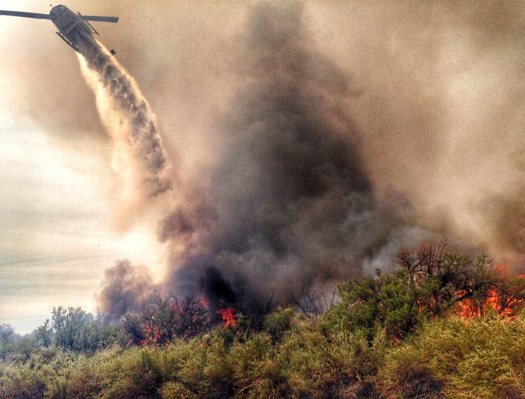 A helicopter makes a drop on a fire which broke out in Arizona and spread into California, sparking the evacuation of two recreational vehicle parks near the Havasu National Wildlife Refuge in Calif. on April 6, 2016.