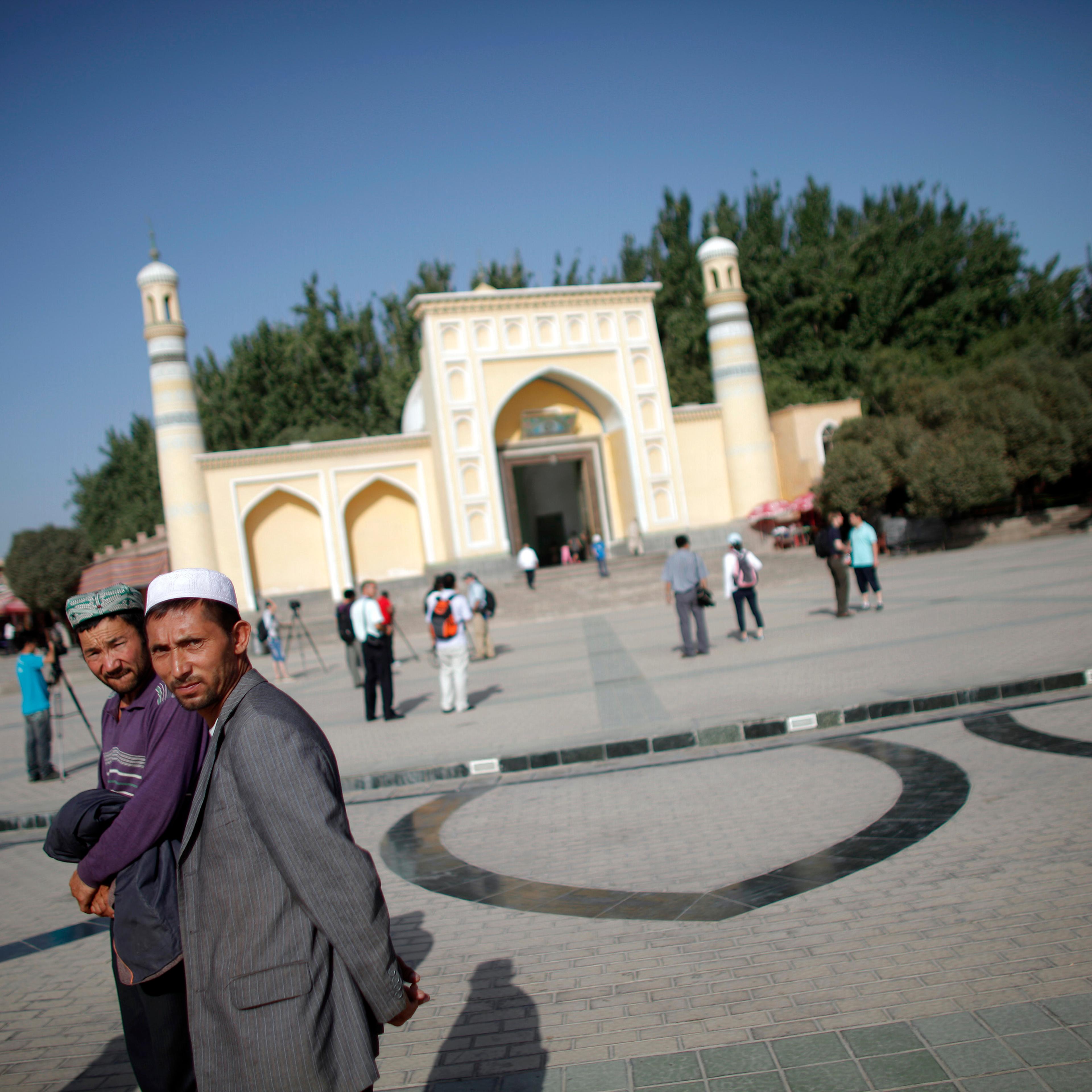Ethnic Uighur men walk outside a mosque in Kashgar