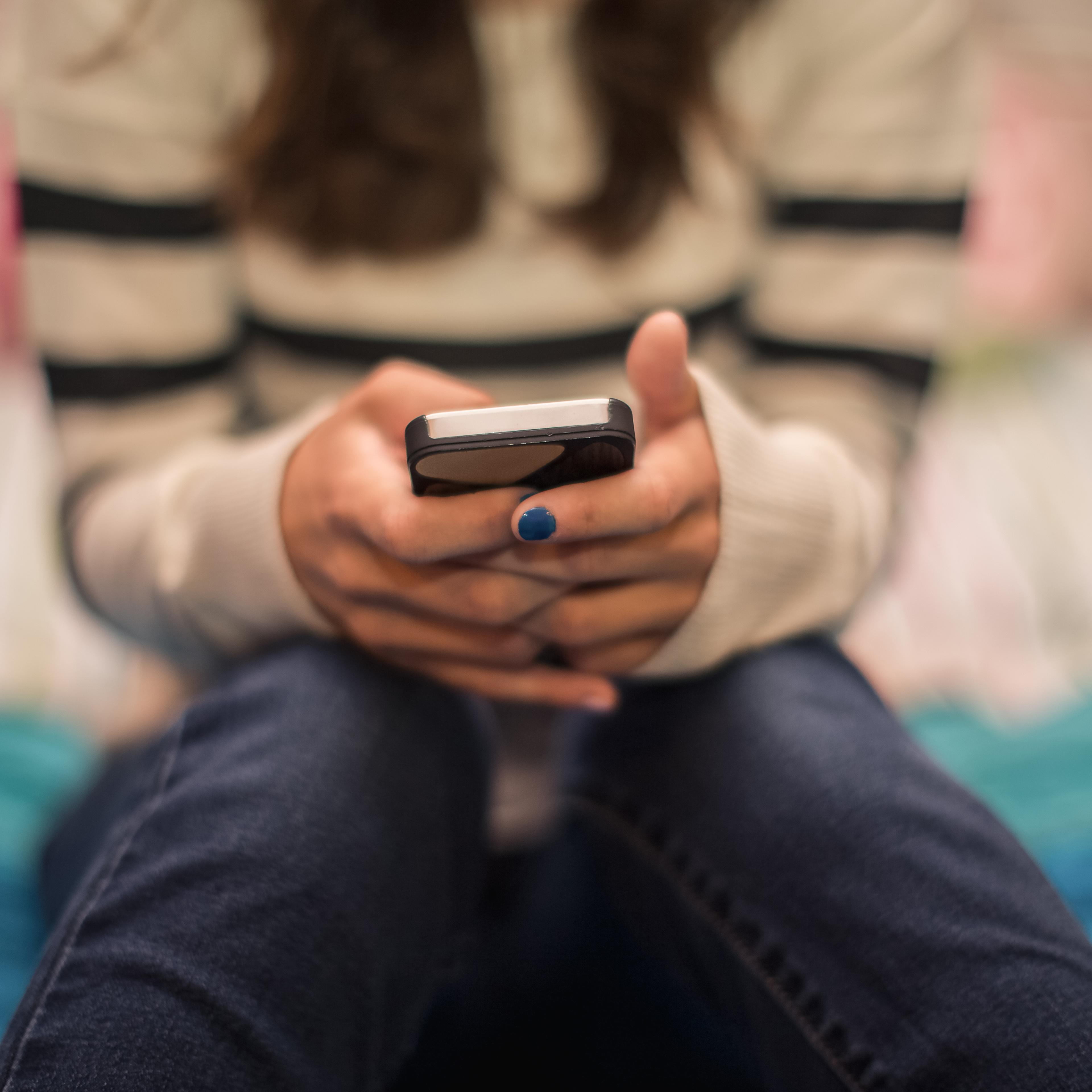 Close up of teenage girl texting on mobile in bedroom