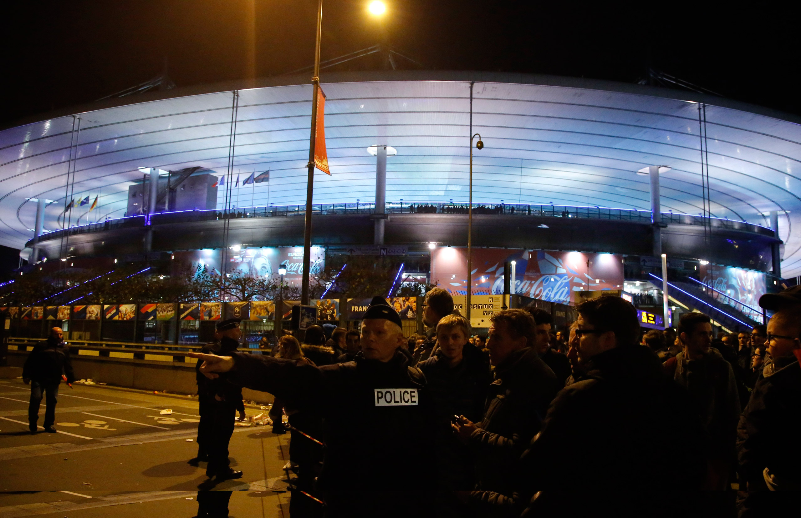 A police officer directs people outside the Stade de France stadium during the international friendly soccer France against Germany, Friday, Nov. 13, 2015 in Saint Denis, outside Paris. Two police officials say at least 11 people have been killed in shoo