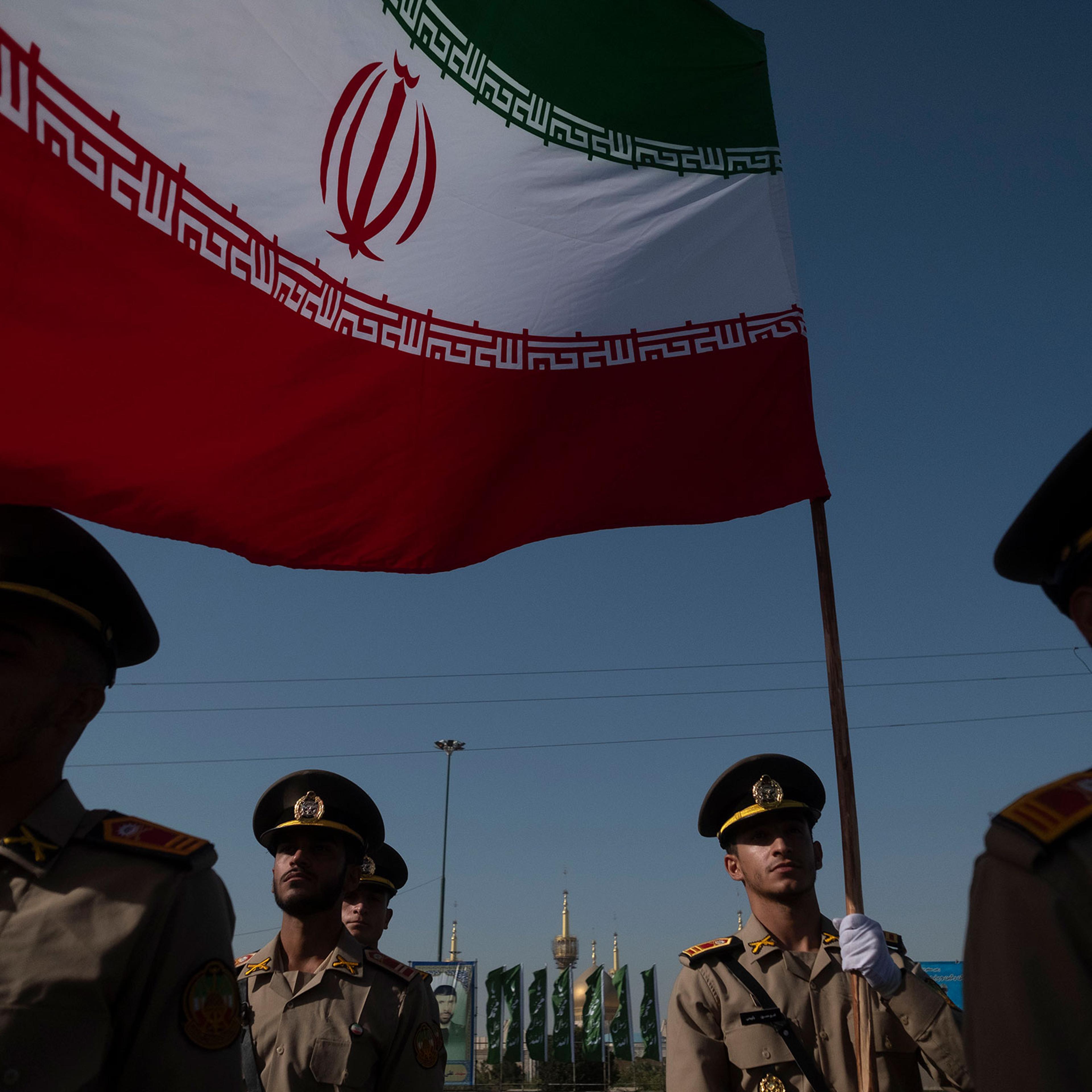 Members of the Iranian Army's land force stand at attention while one of them holds an Iranian flag during a military parade commemorating the anniversary of the Iran-Iraq War (1980-88) outside the Khomeini Shrine in the south of Tehran, Iran, on Sept. 2