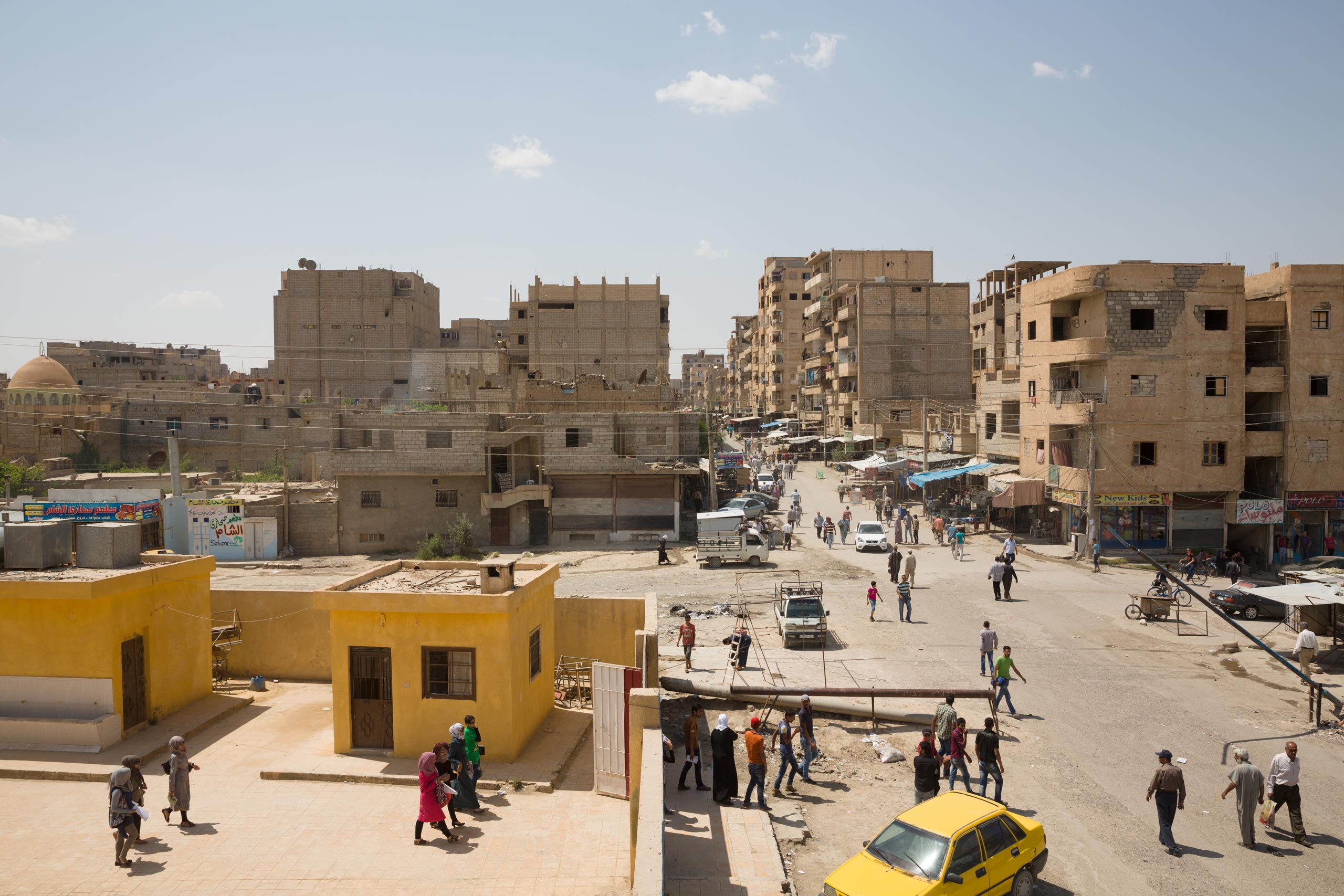 A view of the government-held section of Deir-ez Zor. The children on the left are leaving a school, which is still operating. In a siege that began in December 2014, ISIS fighters have encircled the city in Syria’s eastern desert, May 24, 2015.