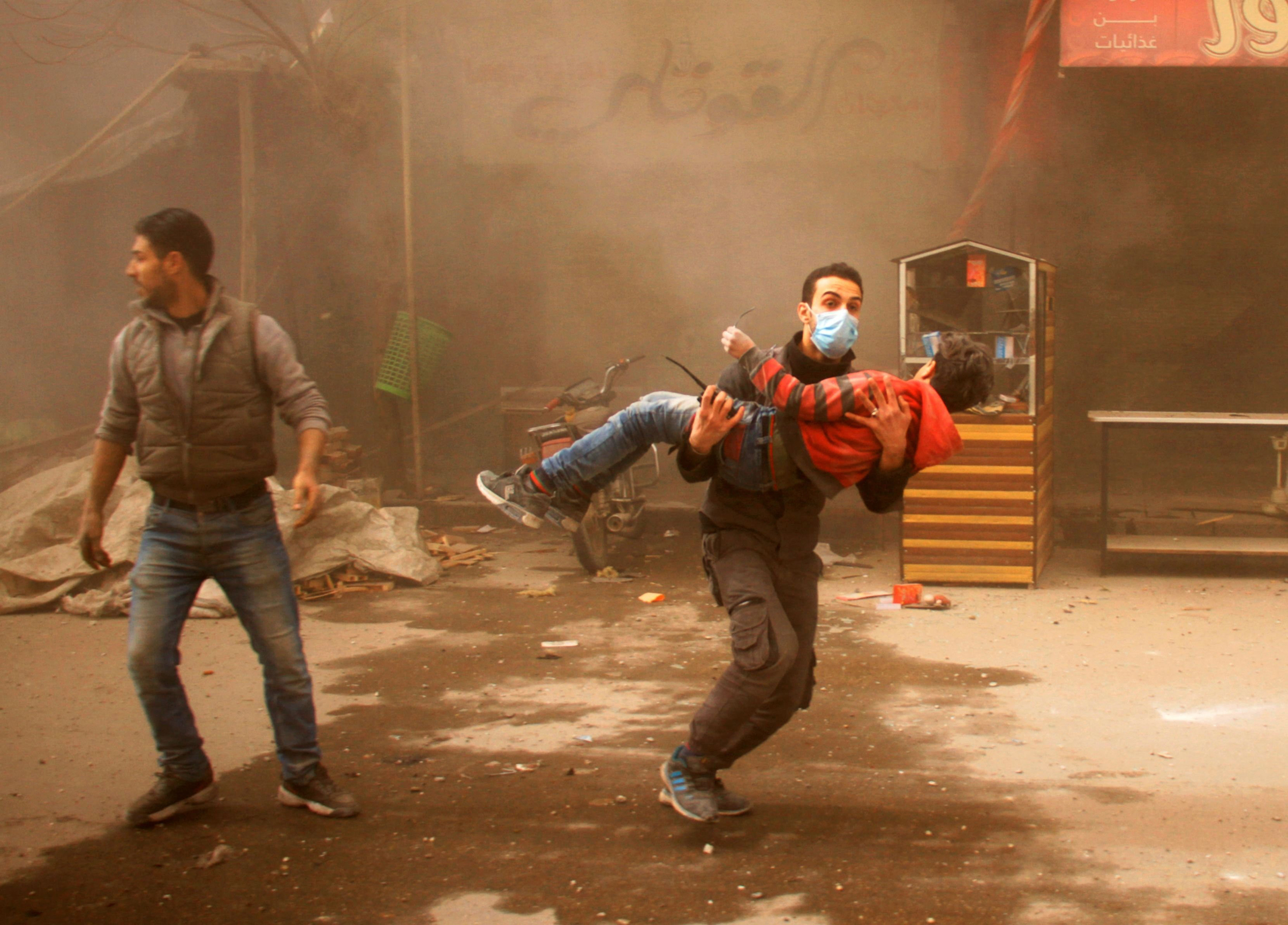 A member of the Syrian Civil Defense carries an injured child following regime air strikes on the rebel-held besieged town of Douma, on the outskirts of the capital Damascus, on Feb. 7, 2018.