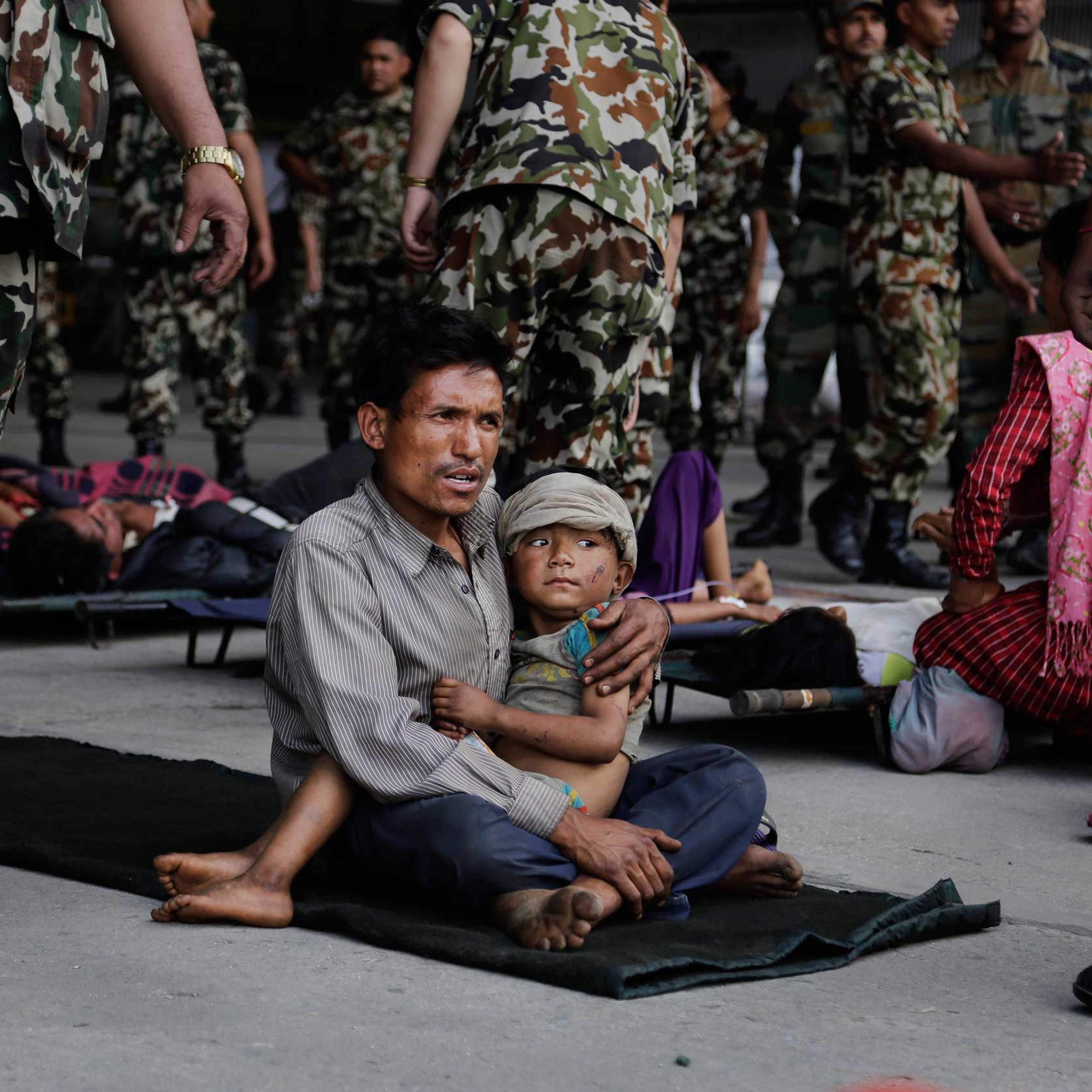 A man sits with a child on his lap as victims of Saturday's earthquake wait for ambulances after being evacuated at the airport in Kathmandu, Nepal, on April 27, 2015.