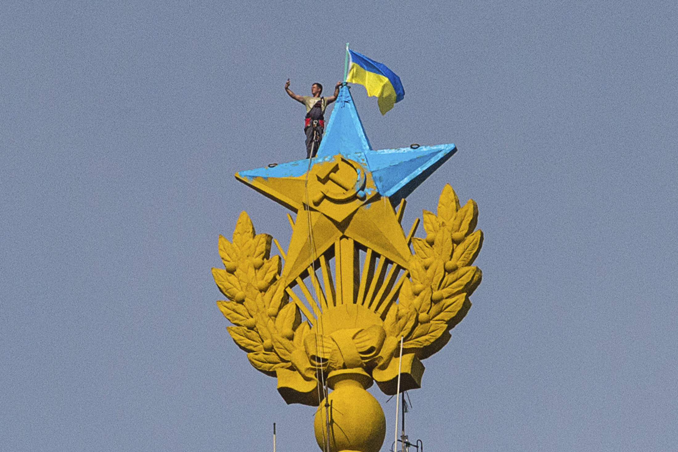 A man takes a "selfie" as he stands with a Ukrainian flag on a Soviet-style star re-touched with blue paint so it resembles the yellow-and-blue national colours of Ukraine, atop the spire of a building in Moscow