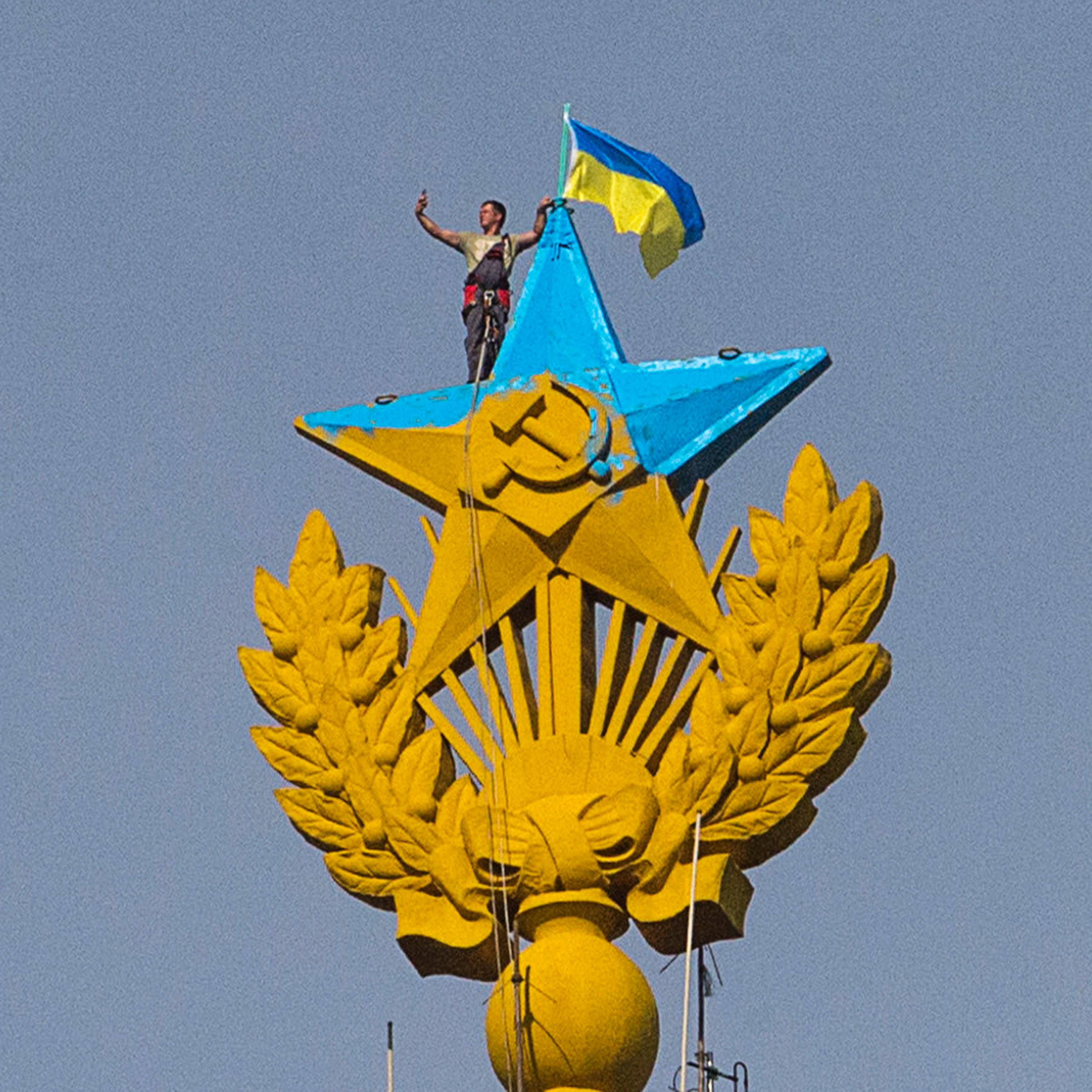 A man takes a "selfie" as he stands with a Ukrainian flag on a Soviet-style star re-touched with blue paint so it resembles the yellow-and-blue national colours of Ukraine, atop the spire of a building in Moscow