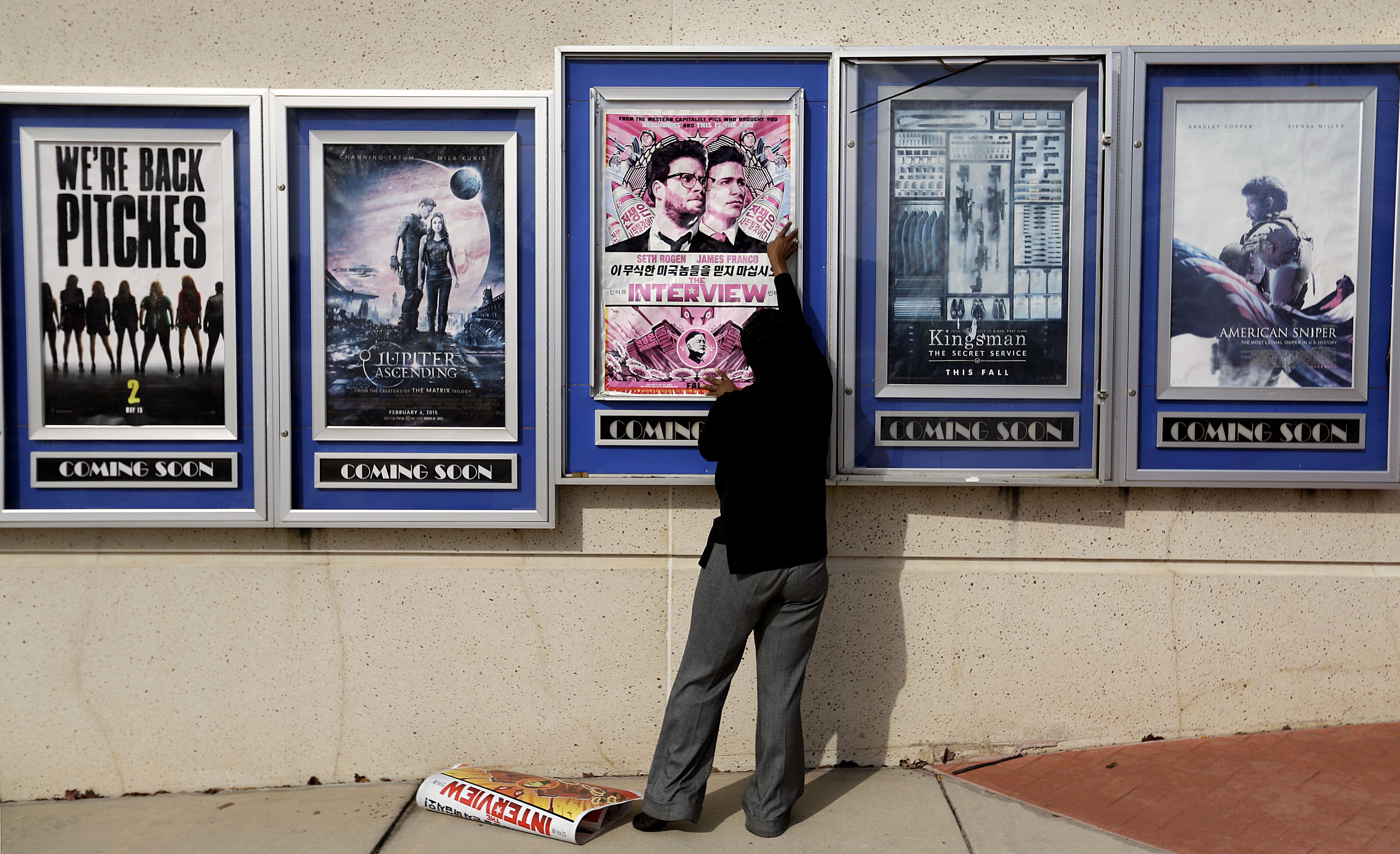 A poster for the movie "The Interview" is taken down by a worker after being pulled from a display case at a Carmike Cinemas movie theater, Wednesday, Dec. 17, 2014, in Atlanta.