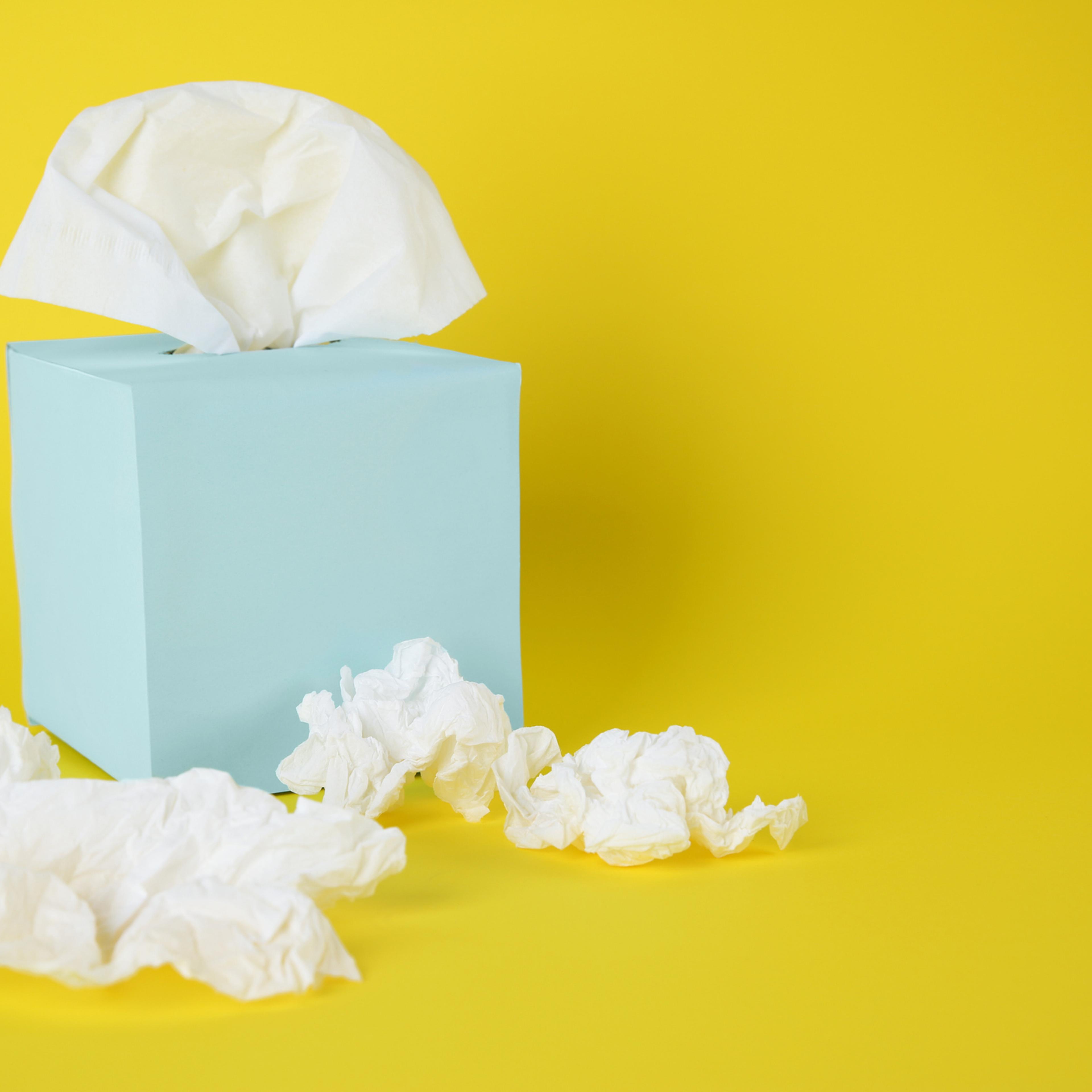 Used paper tissues and box on yellow background. Space for text