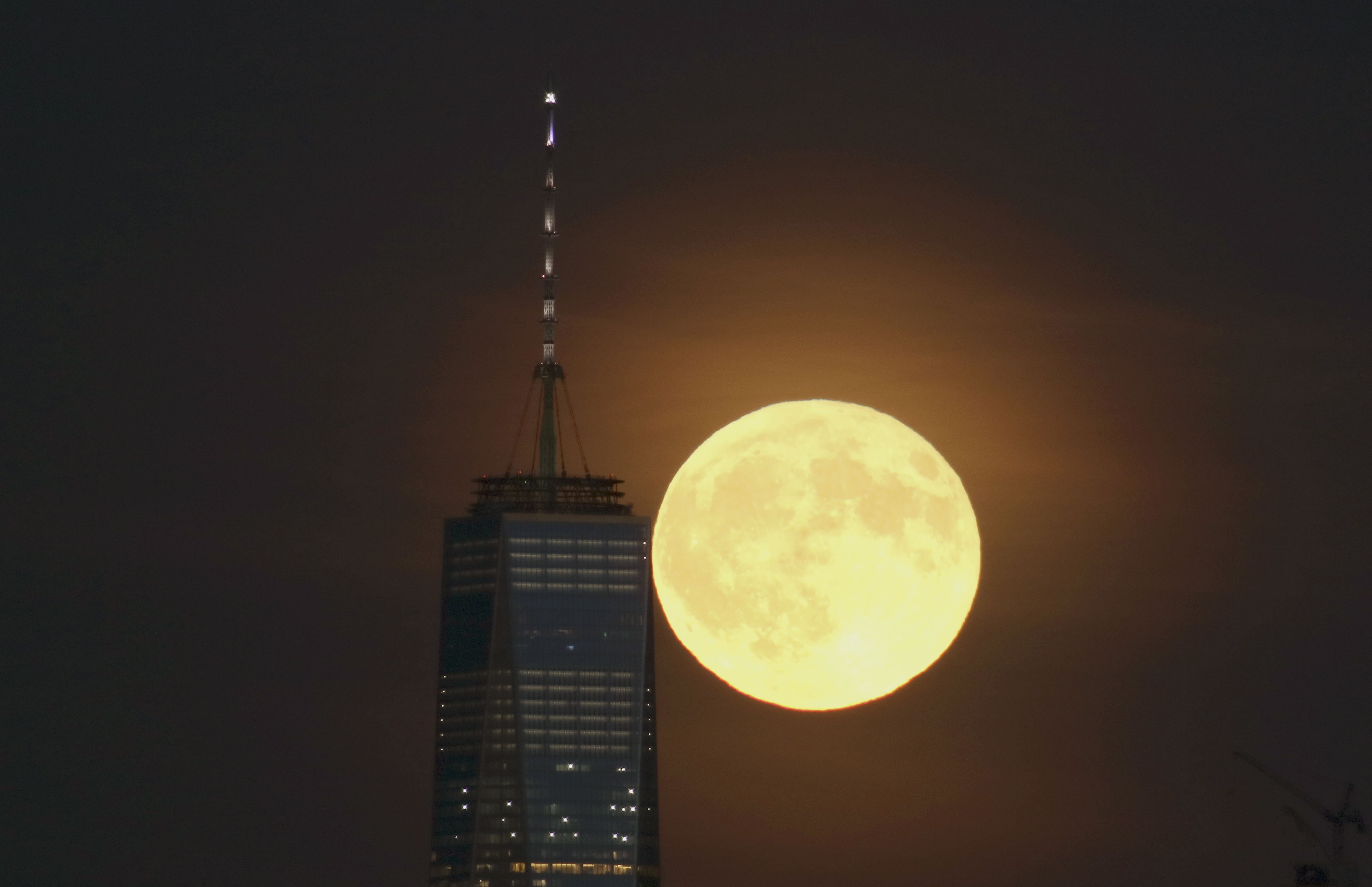 A full harvest moon rises behind Lower Manhattan and One World Trade Center in New York City