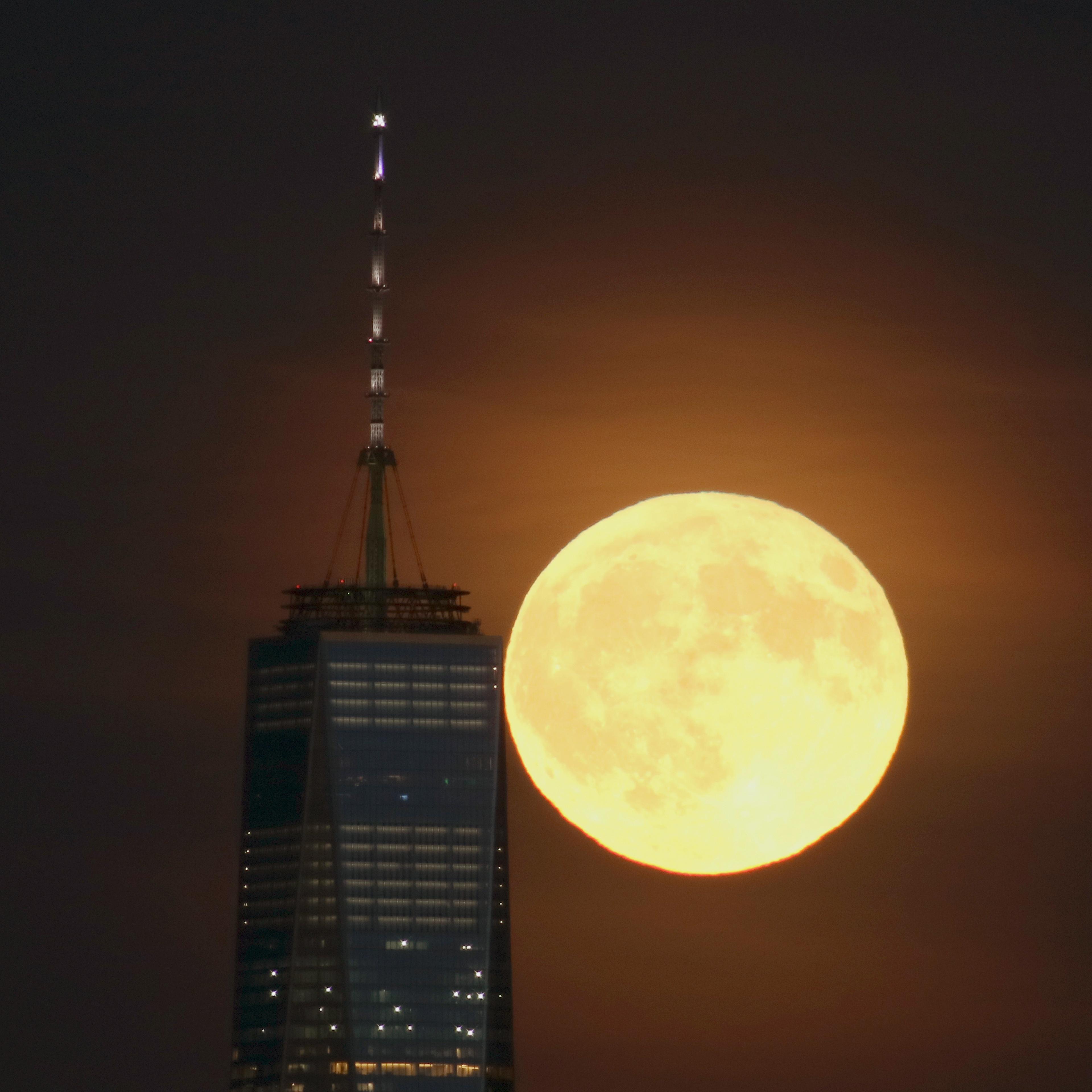 A full harvest moon rises behind Lower Manhattan and One World Trade Center in New York City