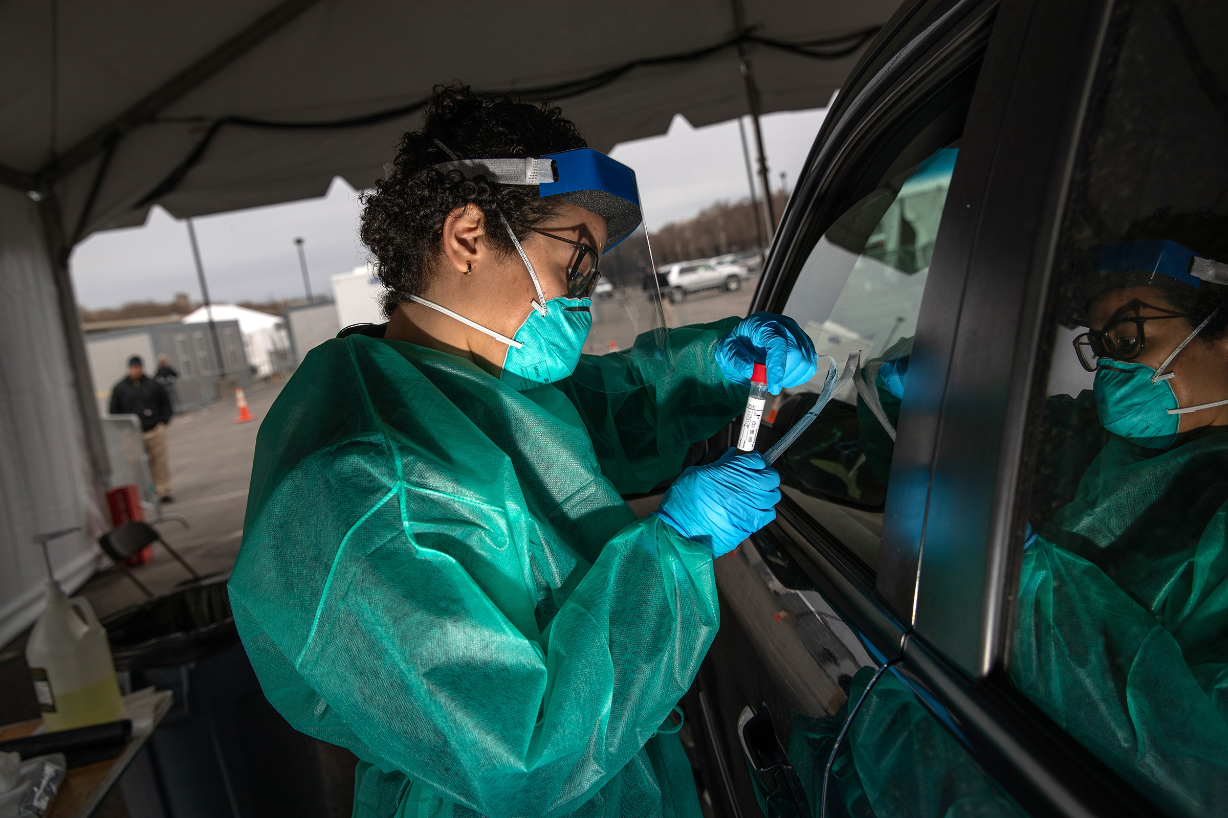 A health worker handles a coronavirus swab test at a drive-thru testing center for COVID-19 at Lehman College on in the Bronx, N.Y., March 28, 2020.