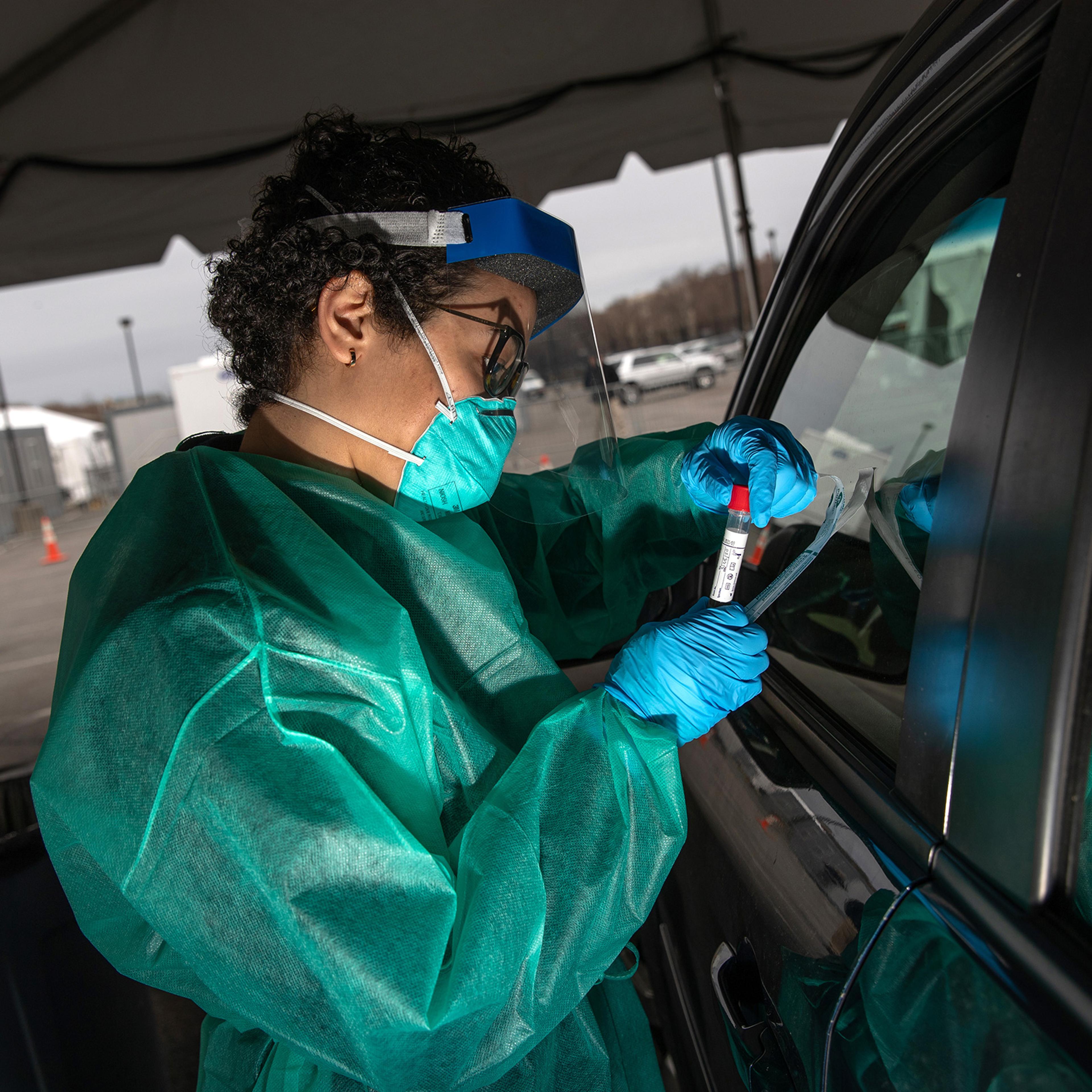 A health worker handles a coronavirus swab test at a drive-thru testing center for COVID-19 at Lehman College on in the Bronx, N.Y., March 28, 2020.
