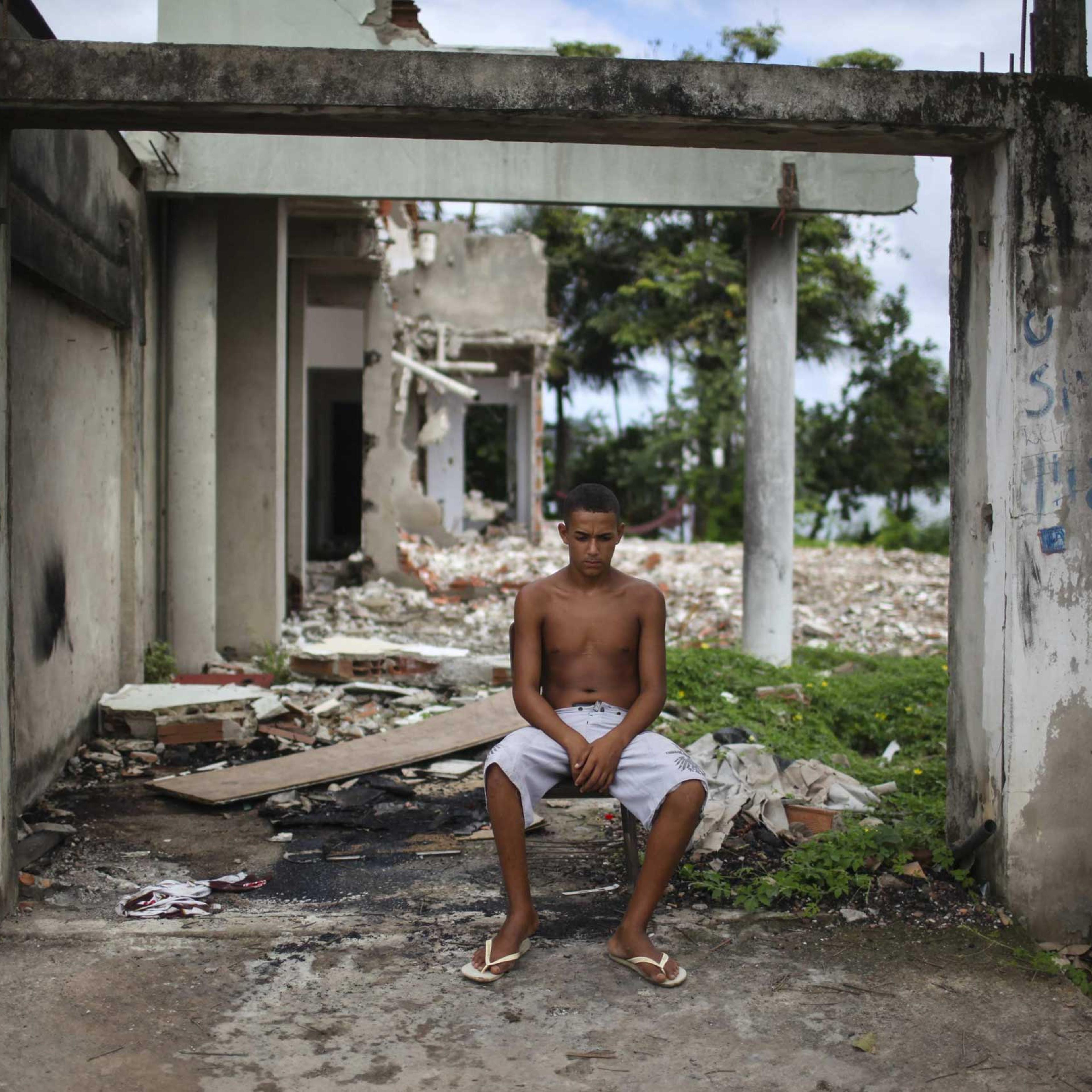 A young man rests next to a destroyed house at the shanty town Vila Autodromo, which is located close to the Olympic Park built for the Olympic Games Rio 2016, in Rio de Janeiro, Brazil, on 01 April 2015.