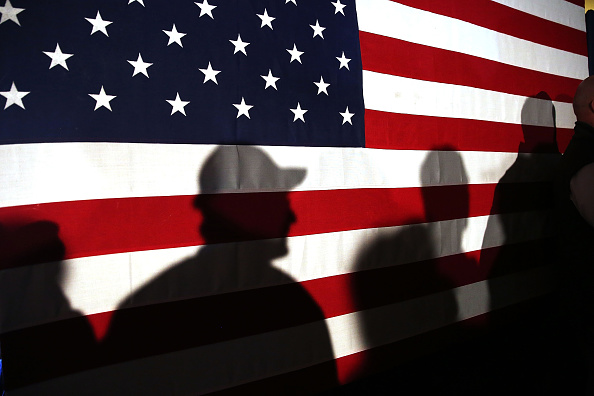 Shadows are reflected on an American Flag as people line up to speak with Ohio Governor and Republican presidential candidate John Kasich at a restaurant in South Carolina following his second place showing in the New Hampshire primary on February 11, 20