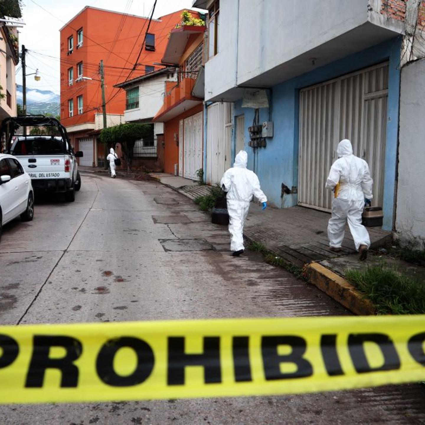 Police investigators in forensic suits inspect the area around the vehicle in which journalist Fredid Román was shot dead, in the state of Guerrero, Mexico, on August 22, 2022.