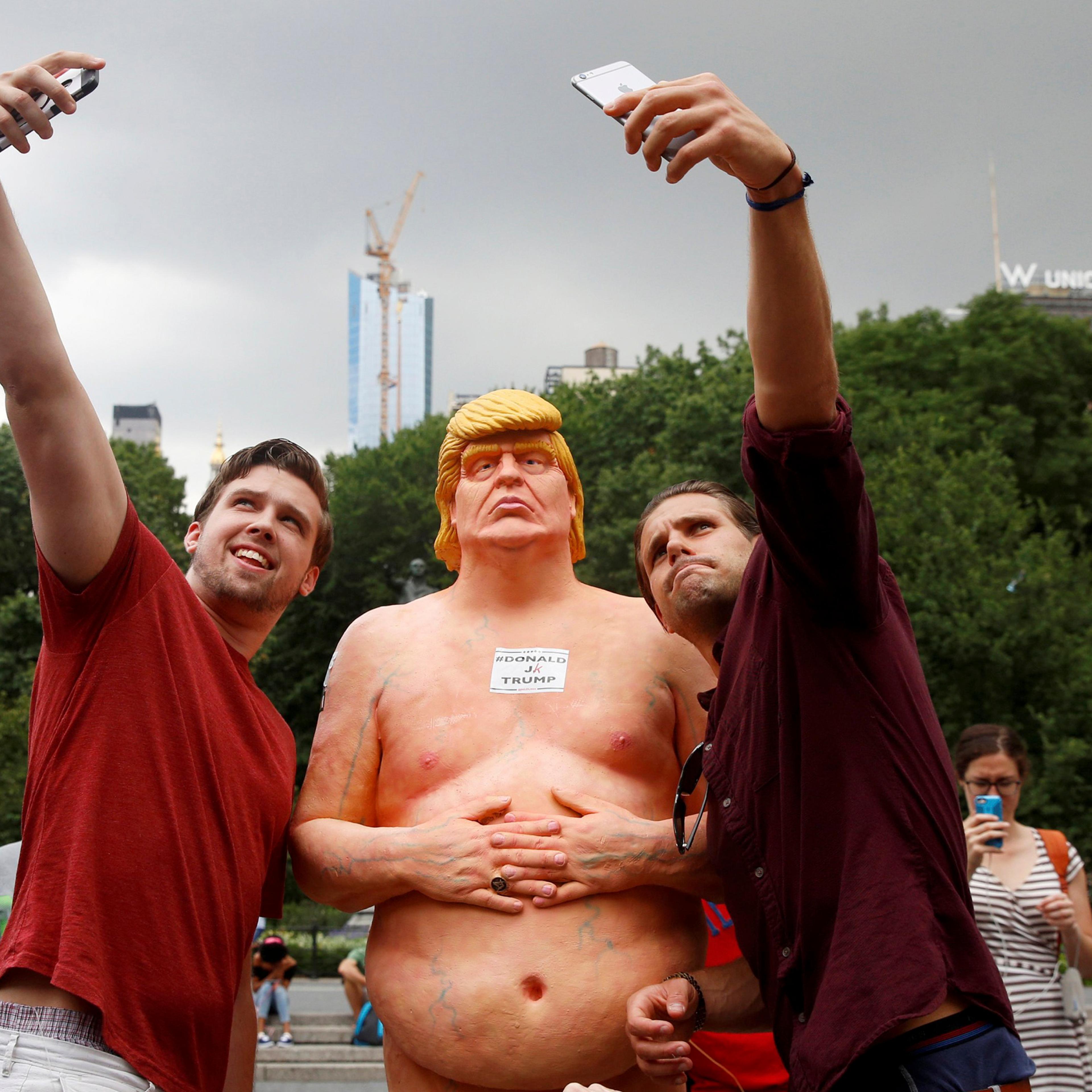 People pose for selfies with a naked statue of U.S. Republican presidential nominee Donald Trump that was left in Union Square Park in New York City on Aug. 18, 2016.