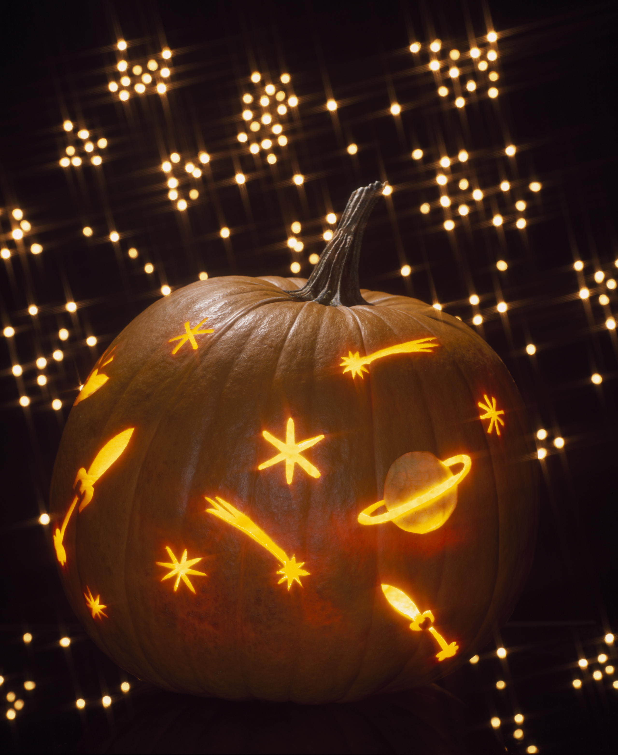 Pumpkin carved as a galaxy of shooting stars and planets