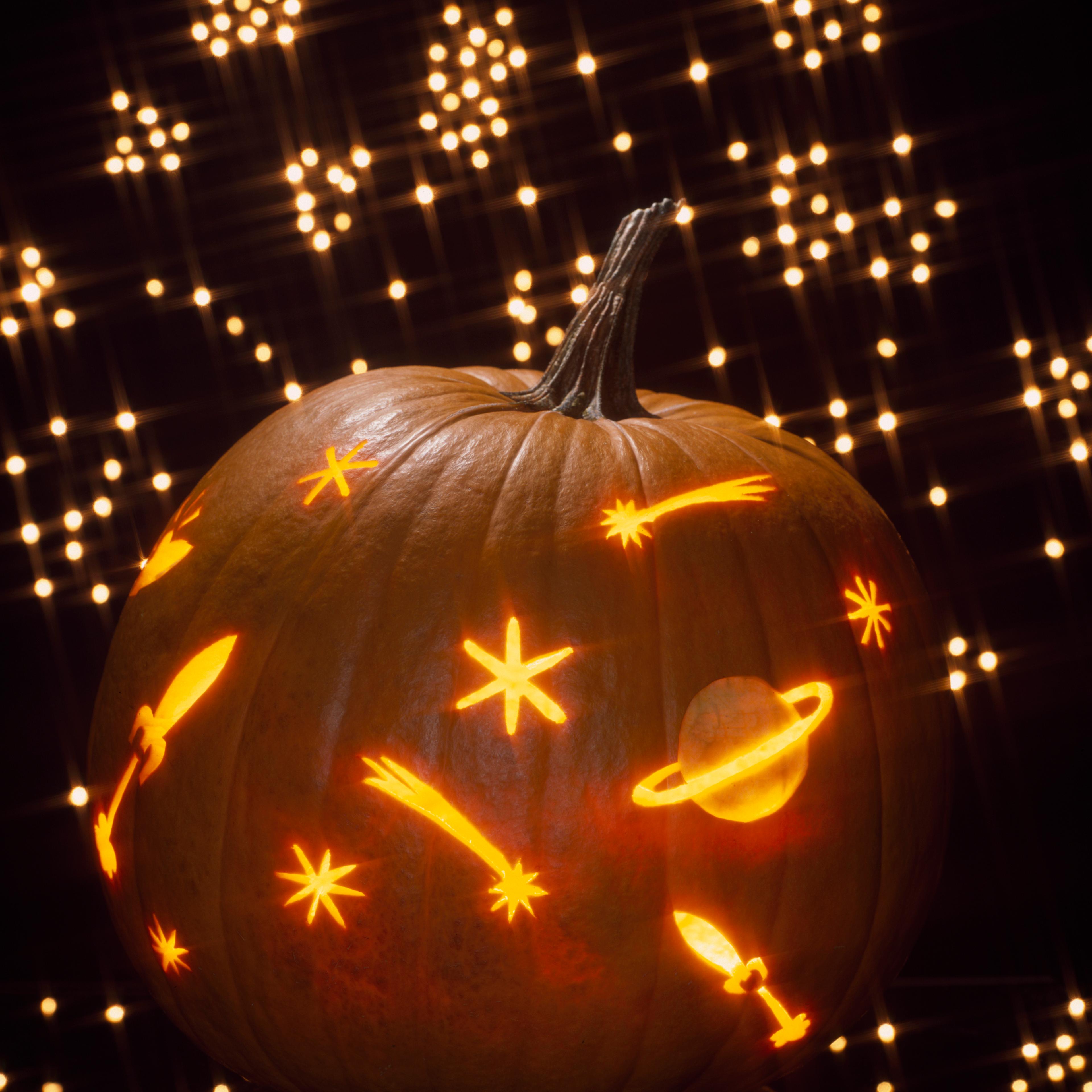 Pumpkin carved as a galaxy of shooting stars and planets