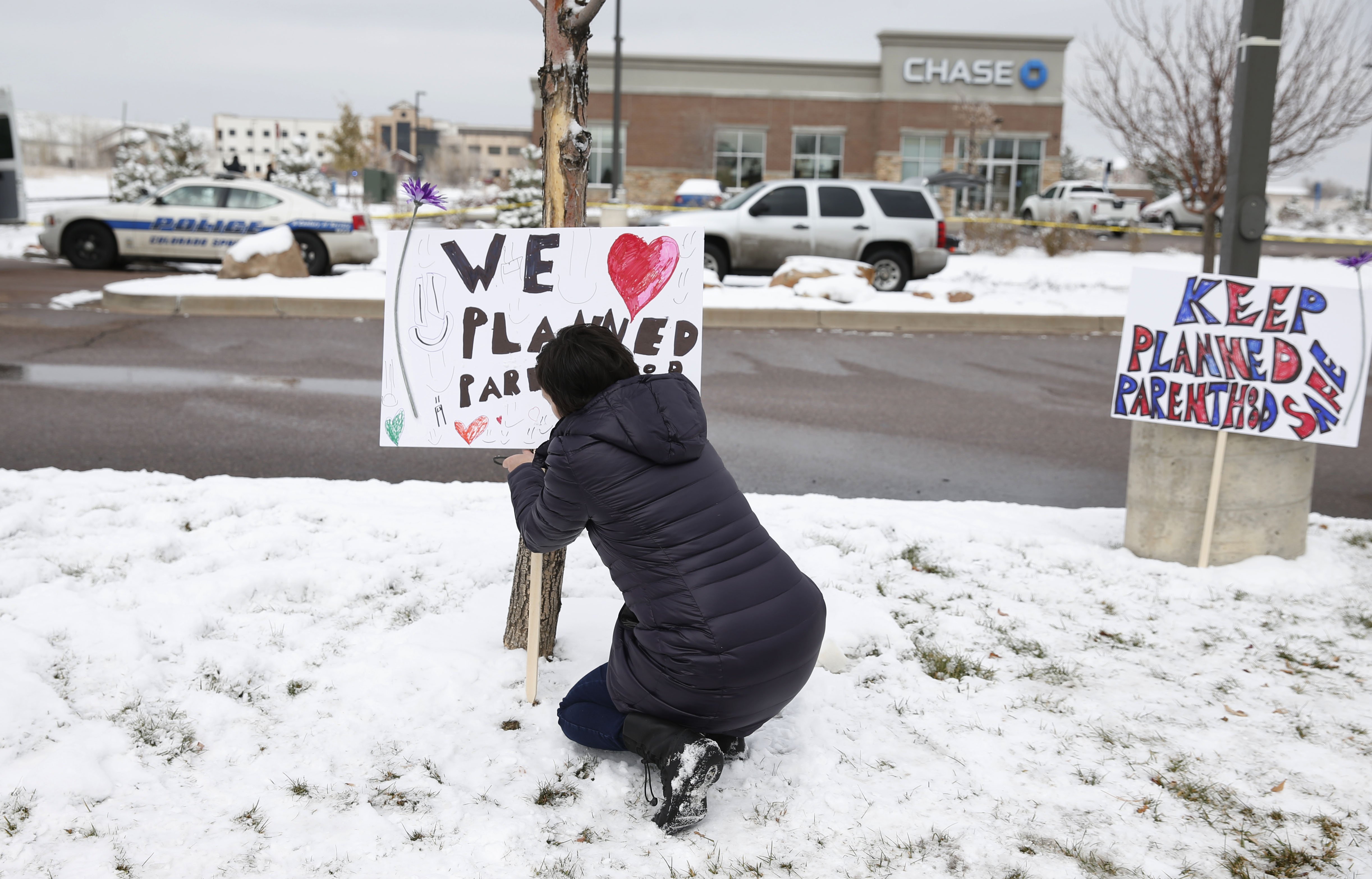 Bethany Winder, a nurse who lives in Colorado Springs, Colo., plants a sign in support of Planned Parenthood just south of its clinic as police investigators gather evidence near the scene of Friday's shooting at the clinic on Nov. 29, 2015.